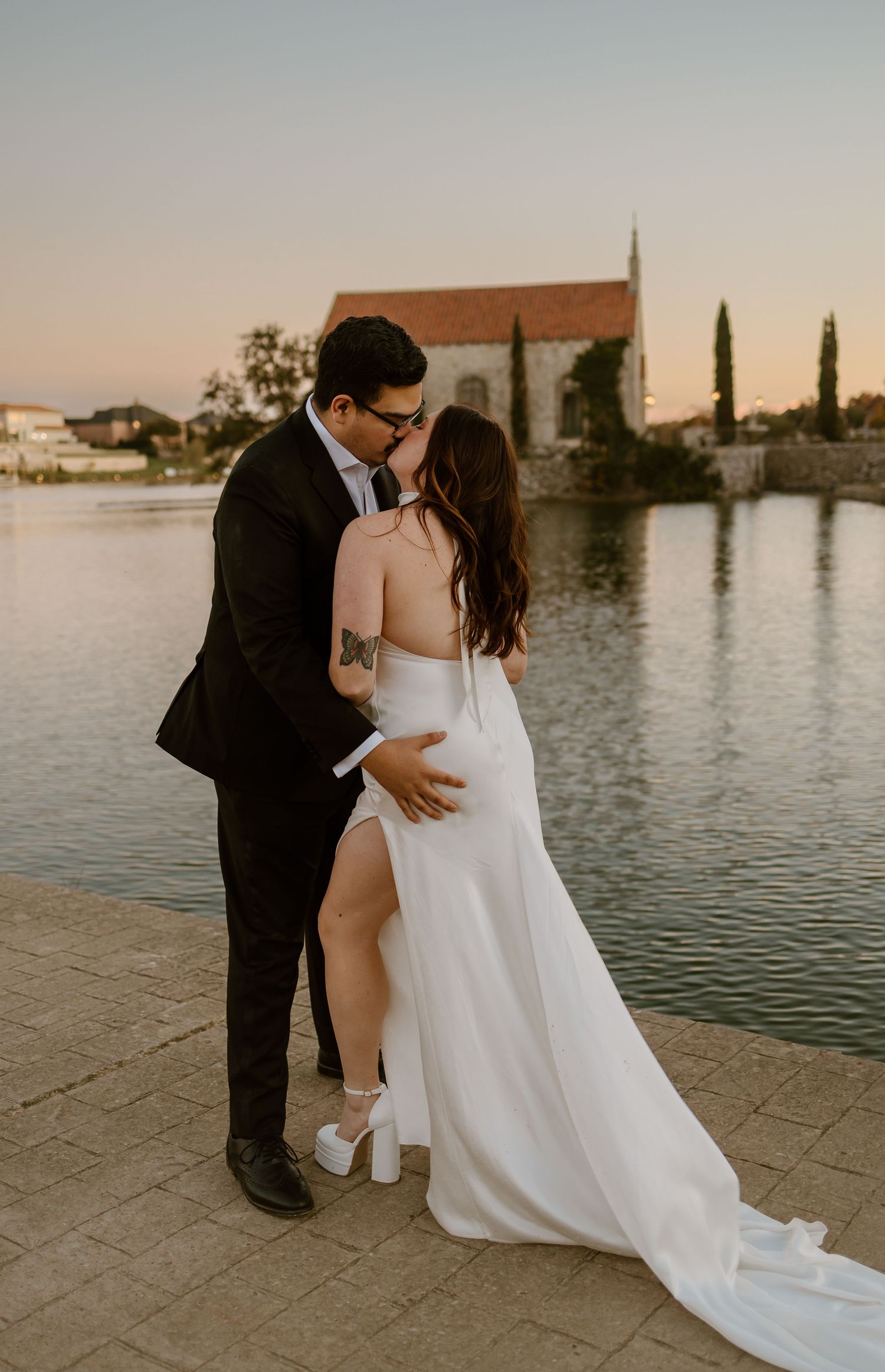 A romantic waterfront wedding portrait with architecture and cypress trees in the background.
