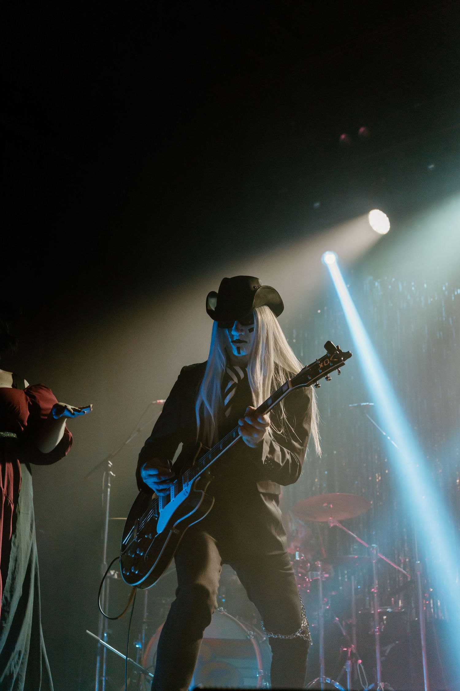Concert performers silhouetted against dramatic blue stage lighting during a live music performance.