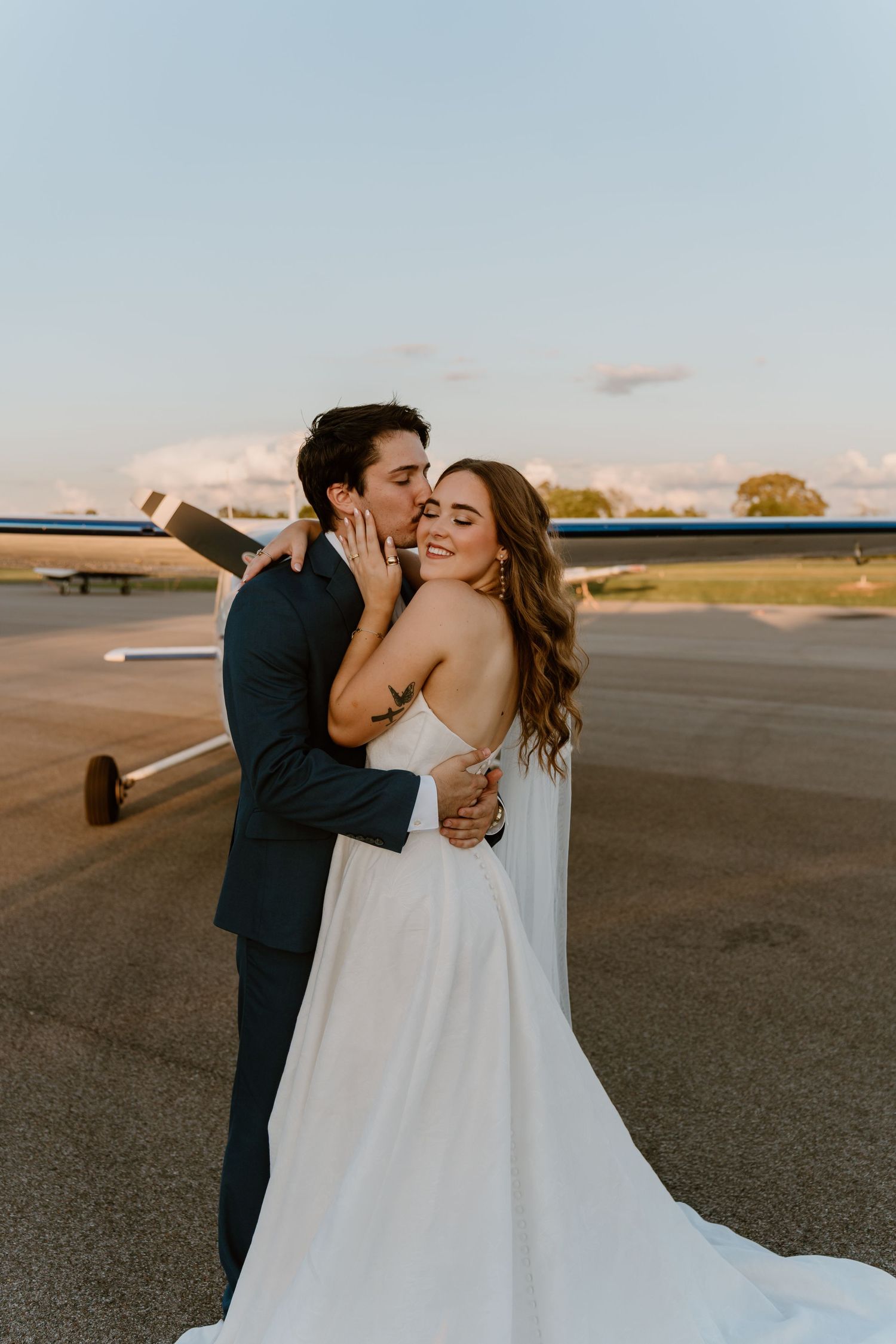 Couple embracing at sunset on an airport runway with planes as the just eloped in Tennessee.
