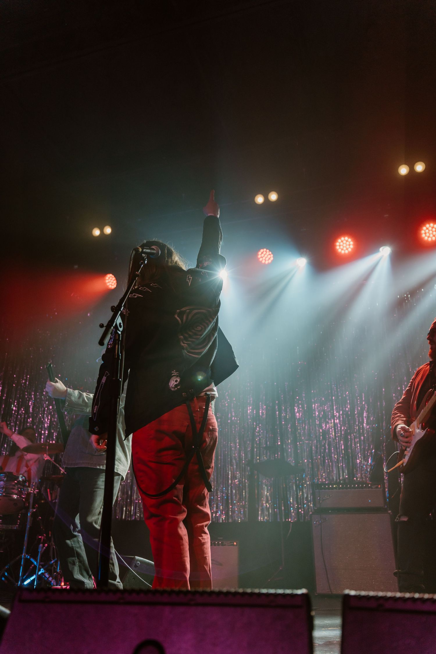 Musicians performing on stage with dramatic red and blue lighting effects.
