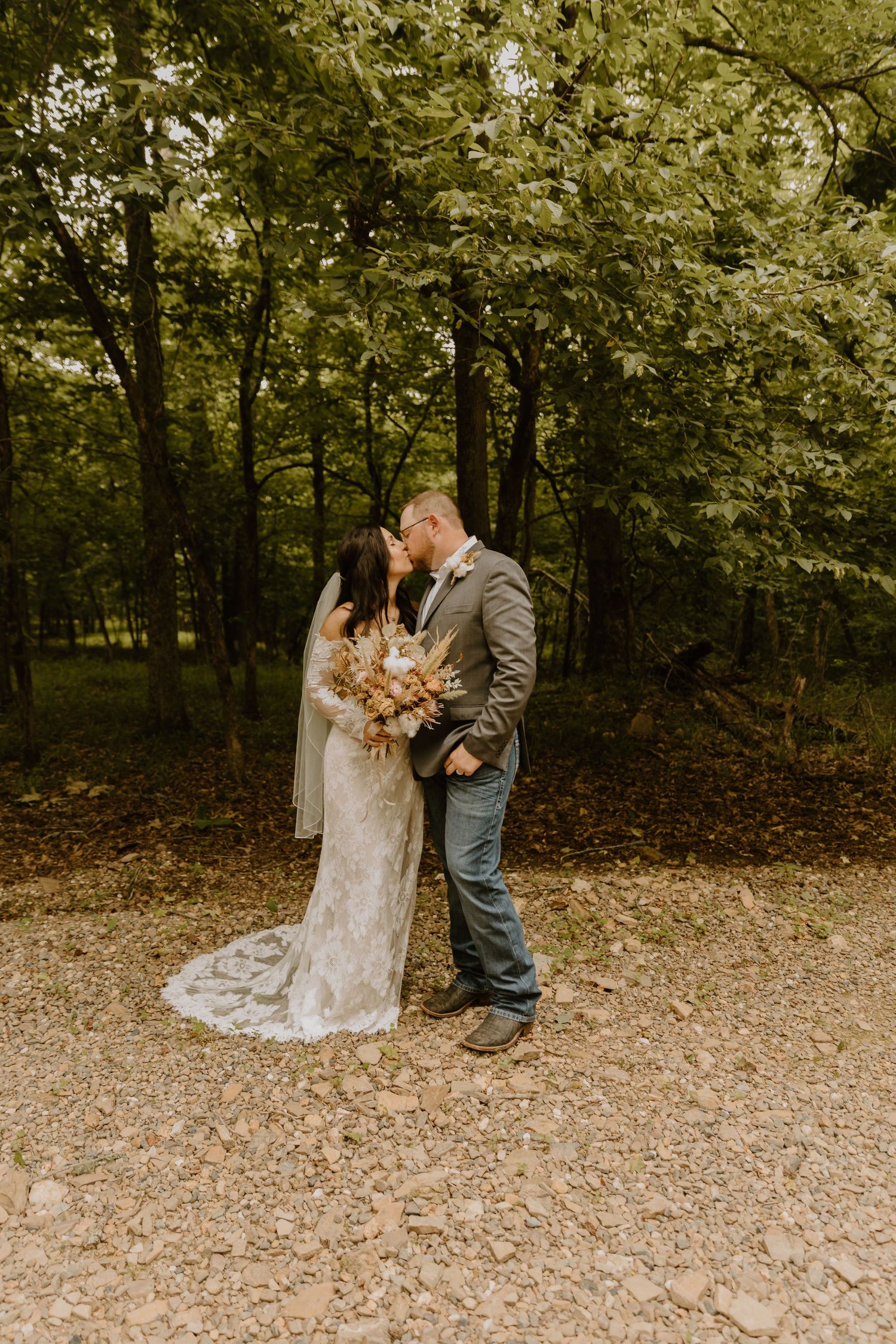 Couple shares intimate moment on fallen leaves in autumn forest setting.