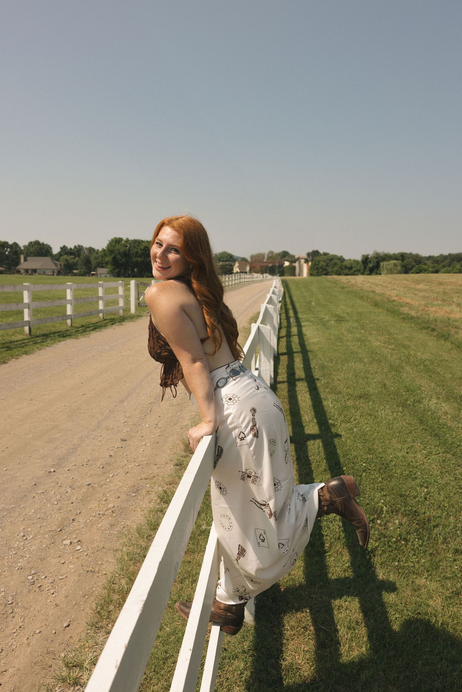 Artistic poses along a white fence on a sunny country path.