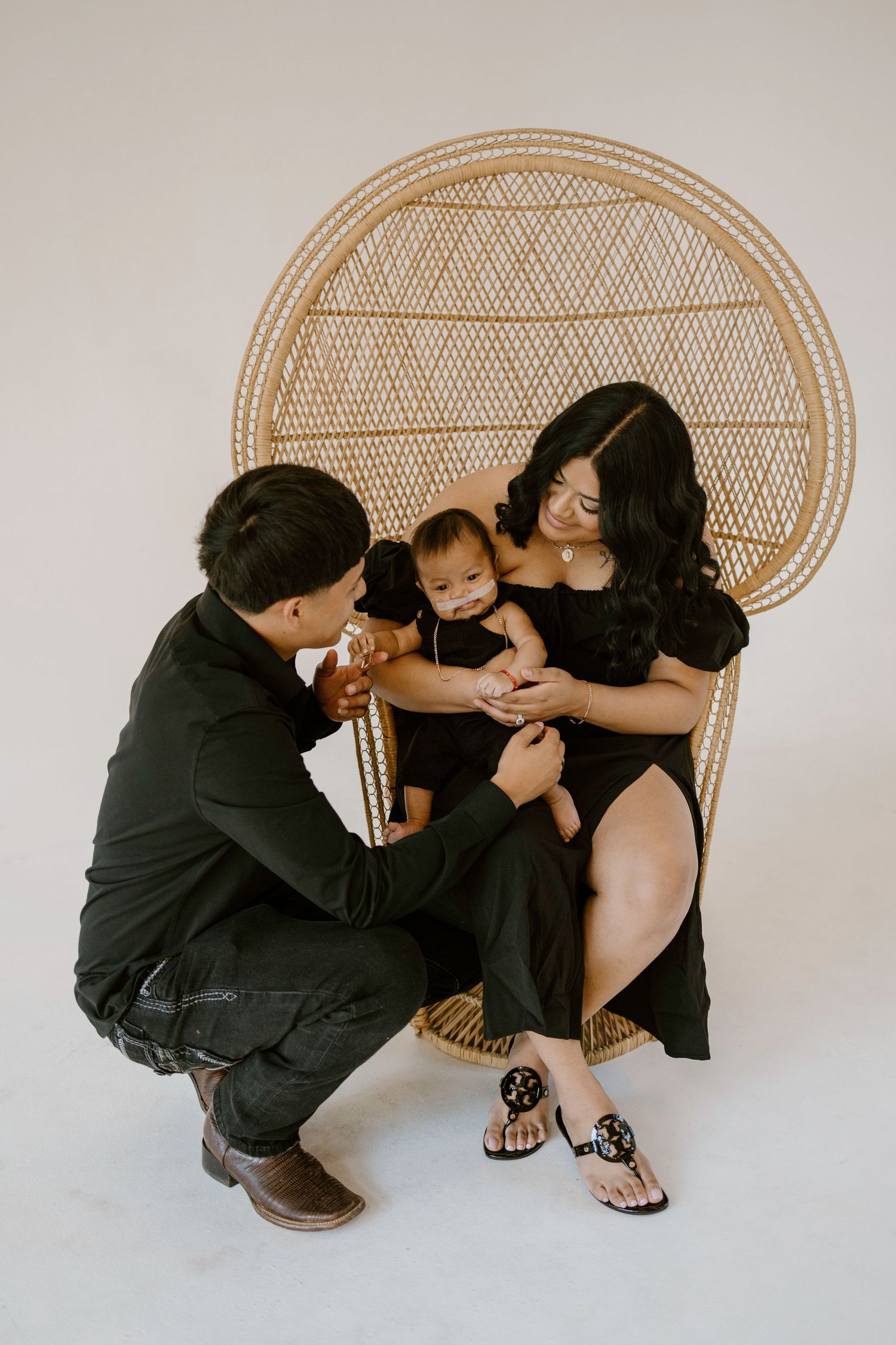 Intimate moments shared on a rattan peacock chair against white background.