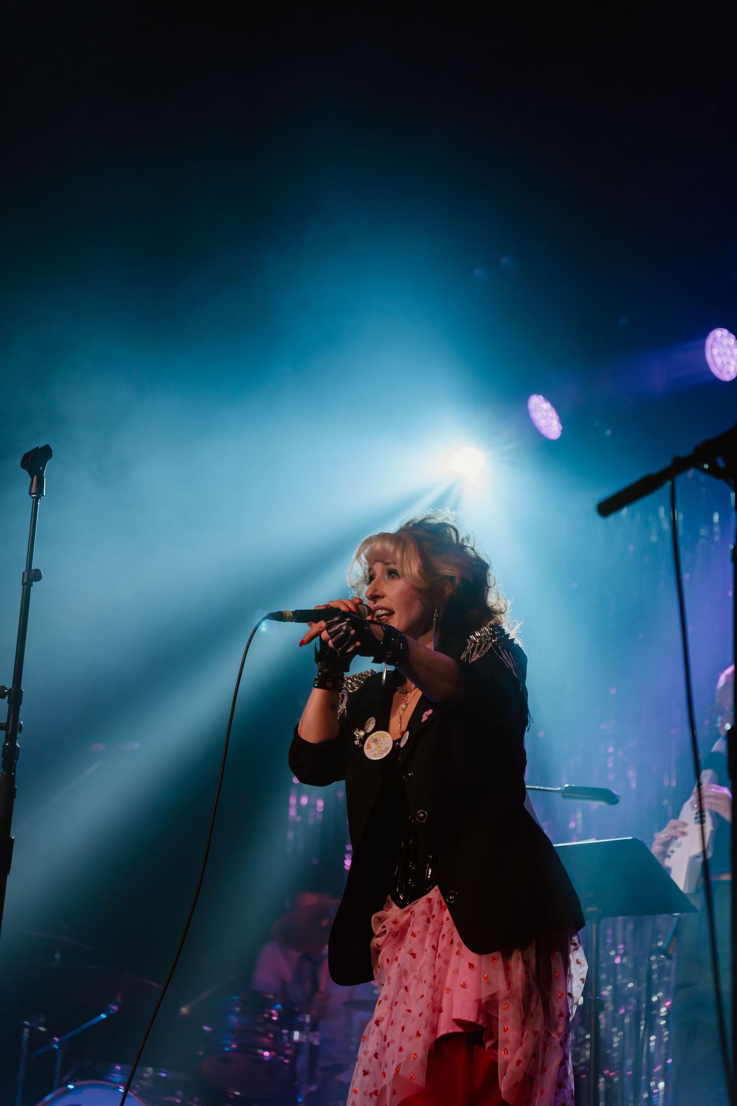 Singer performing on stage with dramatic blue backlighting and fog effects.