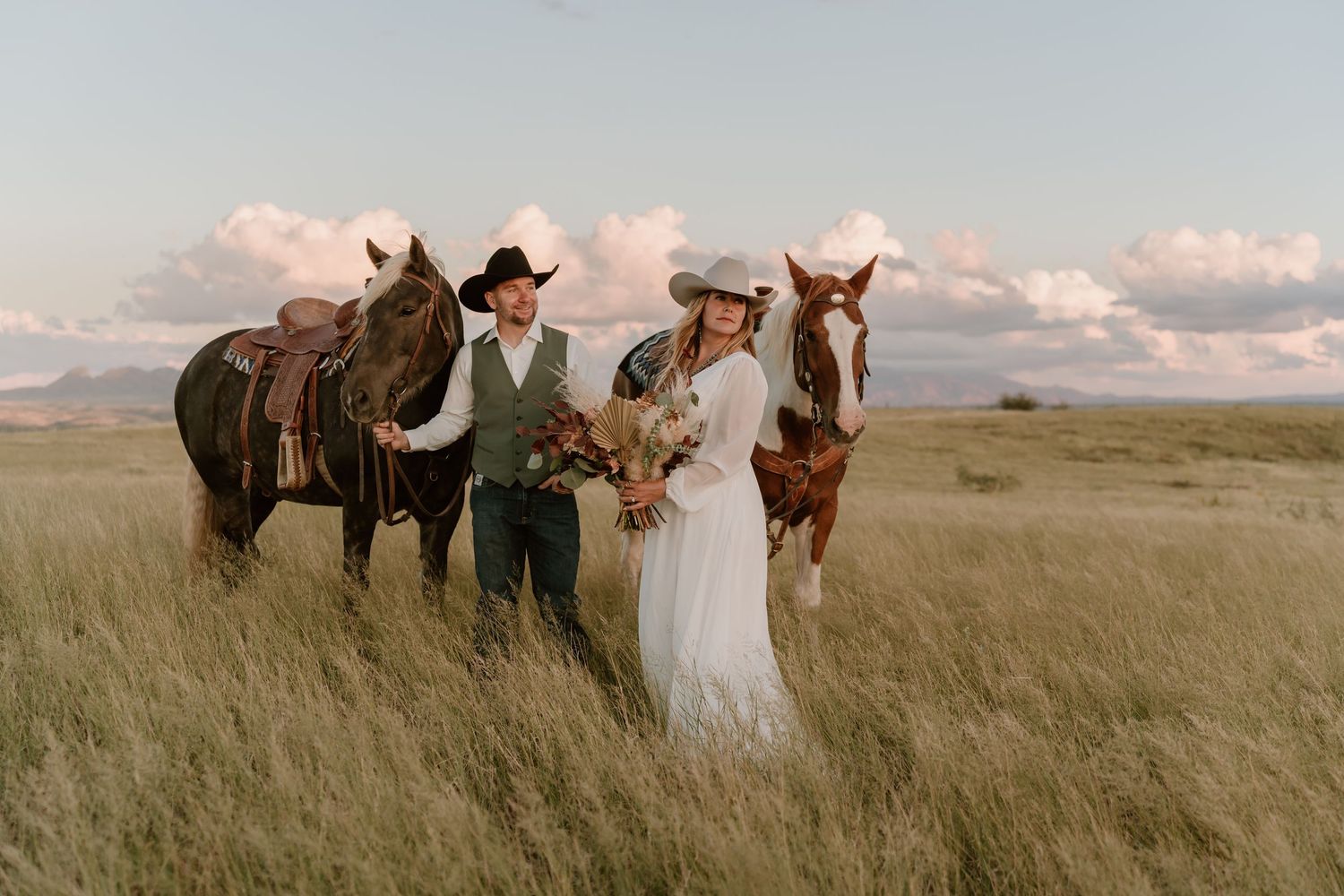 Bride and groom with their horses in a scenic grassland field at sunset in Arizona.