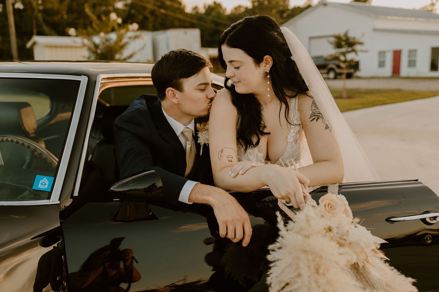 Romantic moments captured near a vintage car during a wedding photoshoot.