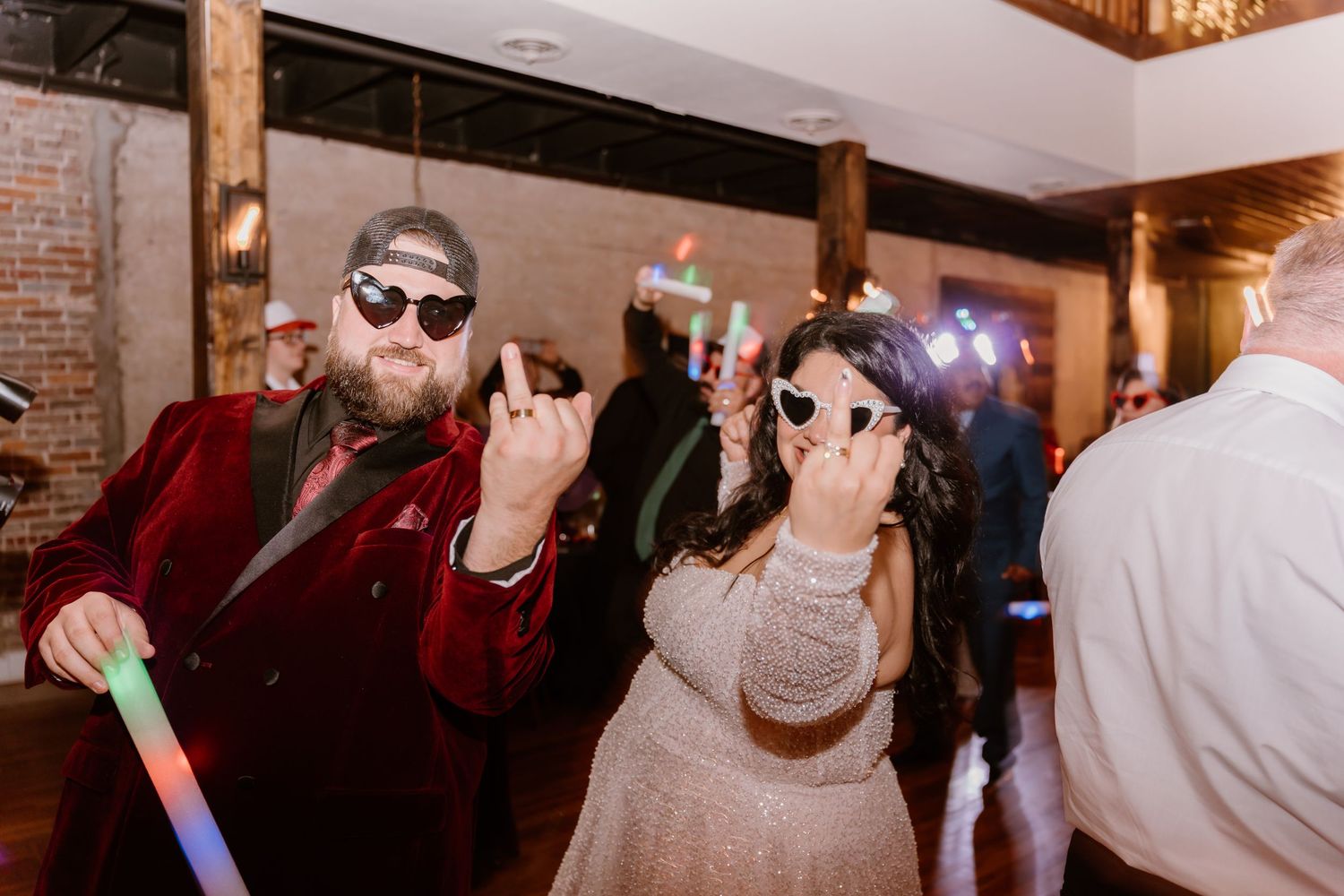 Wedding couple celebrating at indoor reception with brick walls and chandelier.