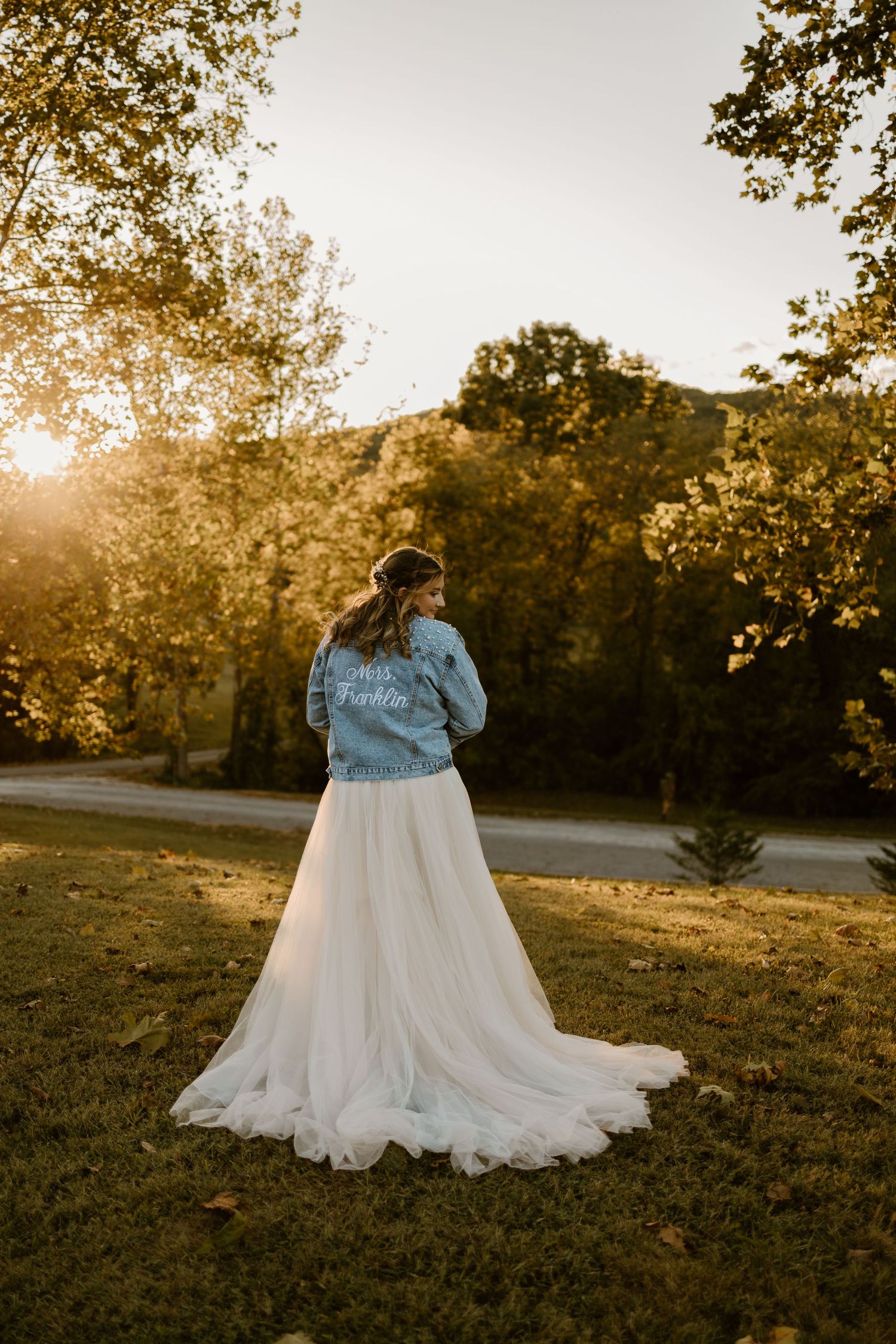 A wedding dress flows beautifully across grass during an outdoor autumn photoshoot.