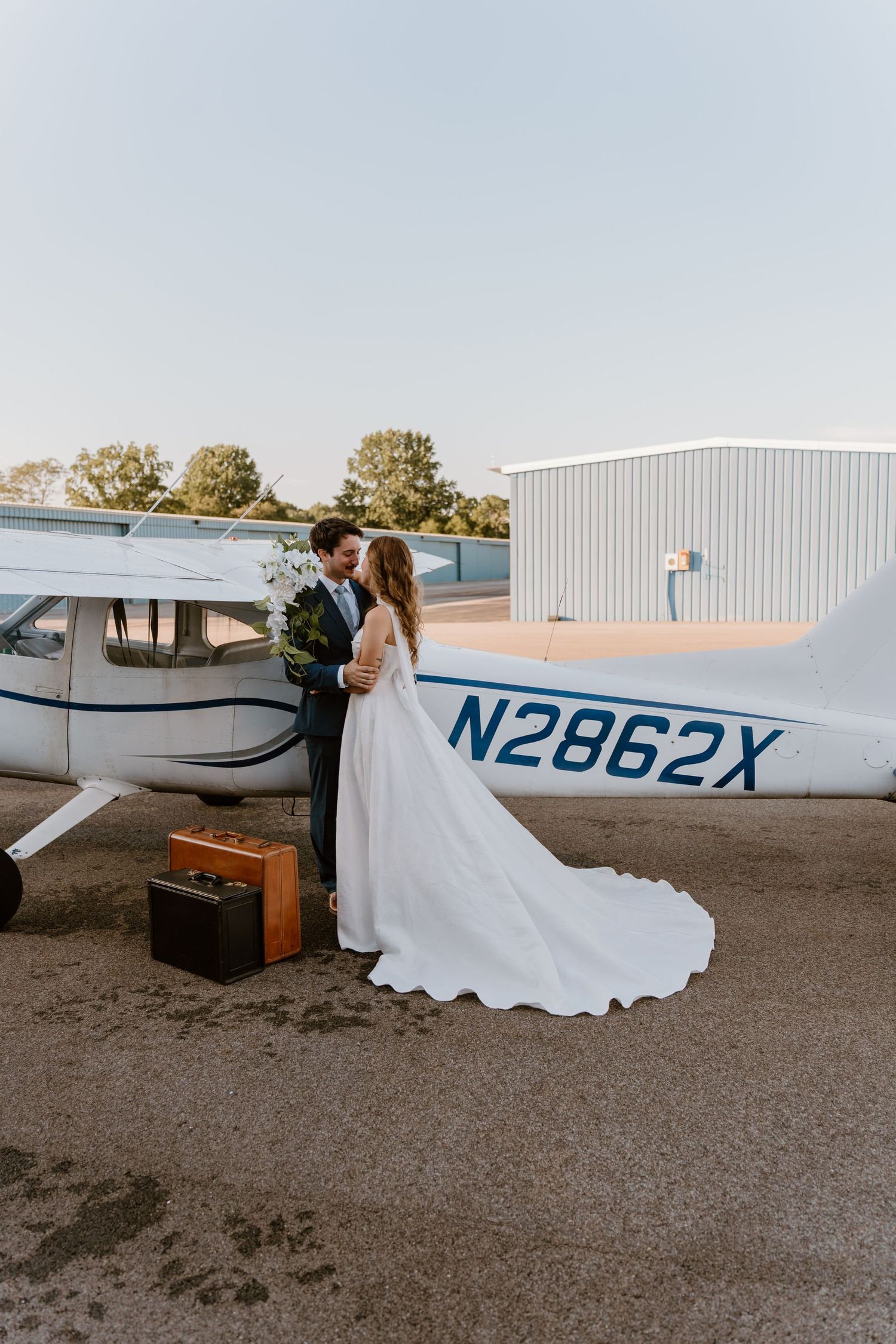 A romantic wedding photo shoot next to a small private airplane on a tarmac.