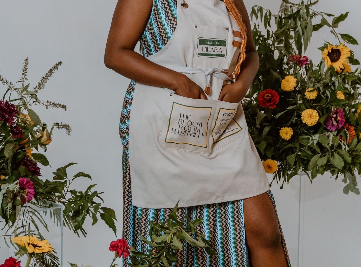 Close-up of white apron with pocket detail against floral backdrop.