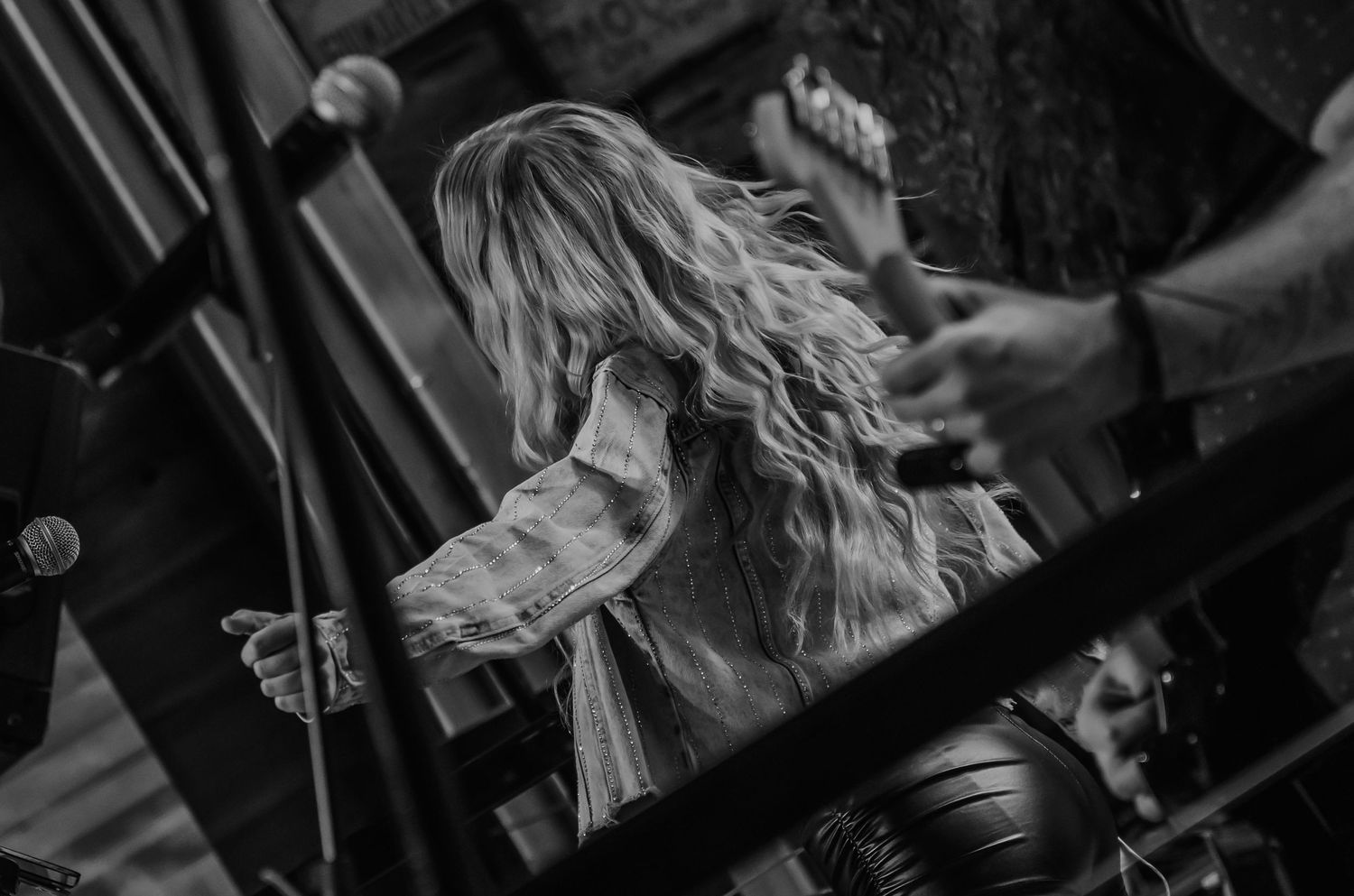Black and white photo of a long-haired performer on stage during a live music concert.