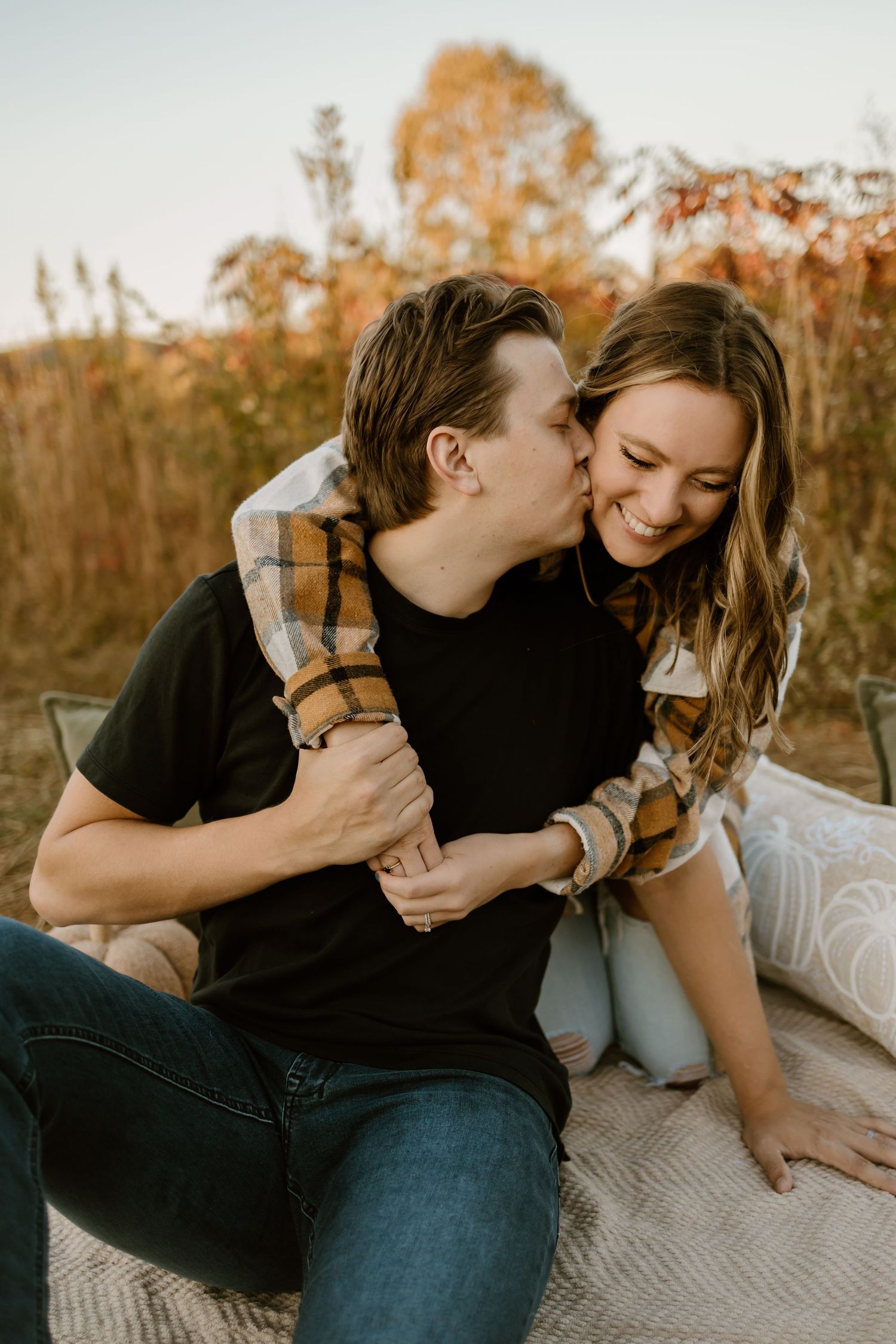 A couple laughs together during a casual outdoor photoshoot at sunset.