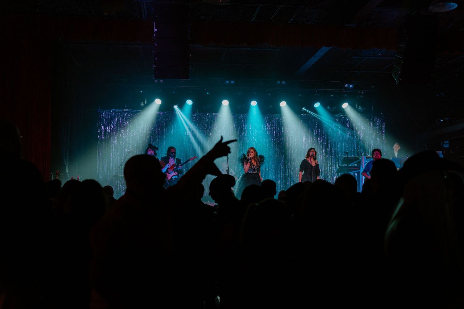 Concert crowd silhouettes against blue stage lights during a live performance.