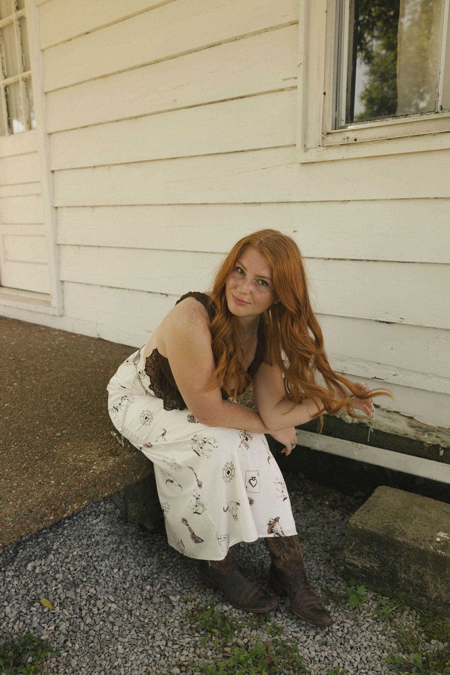 Artistic portrait session against a white farmhouse wall with gravel ground.