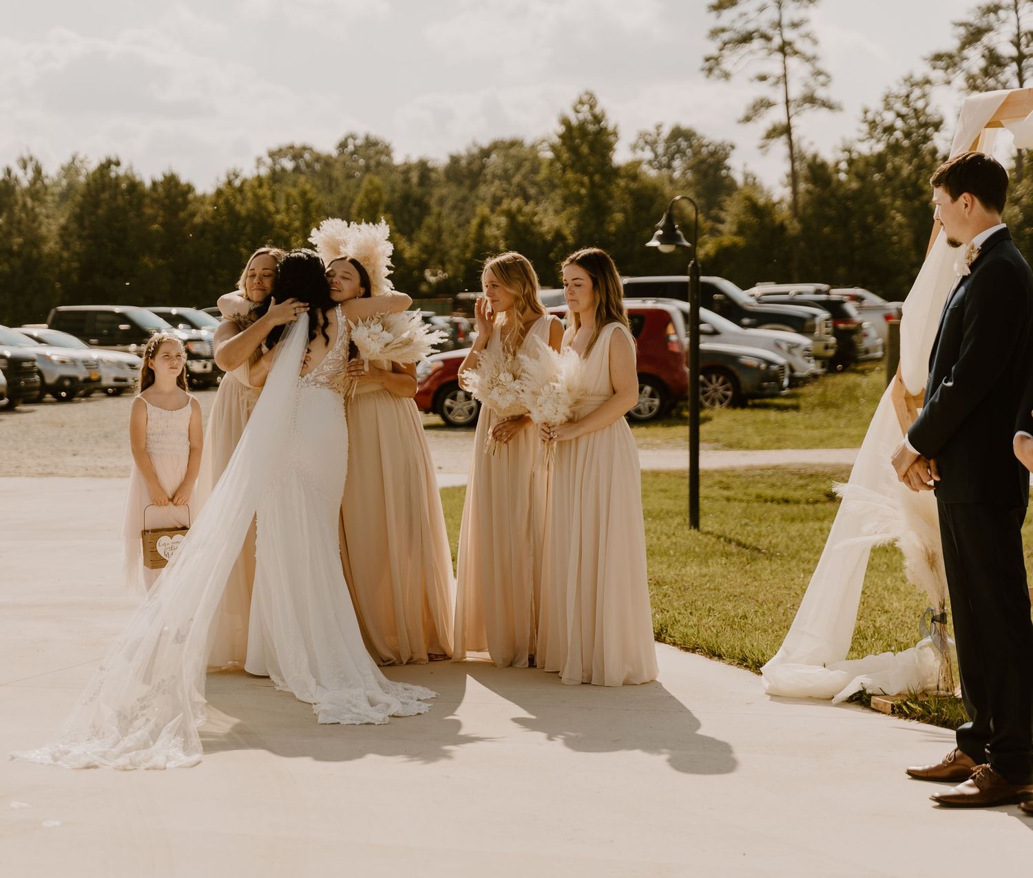 Wedding party members in formal attire gather outside on a sunny day.