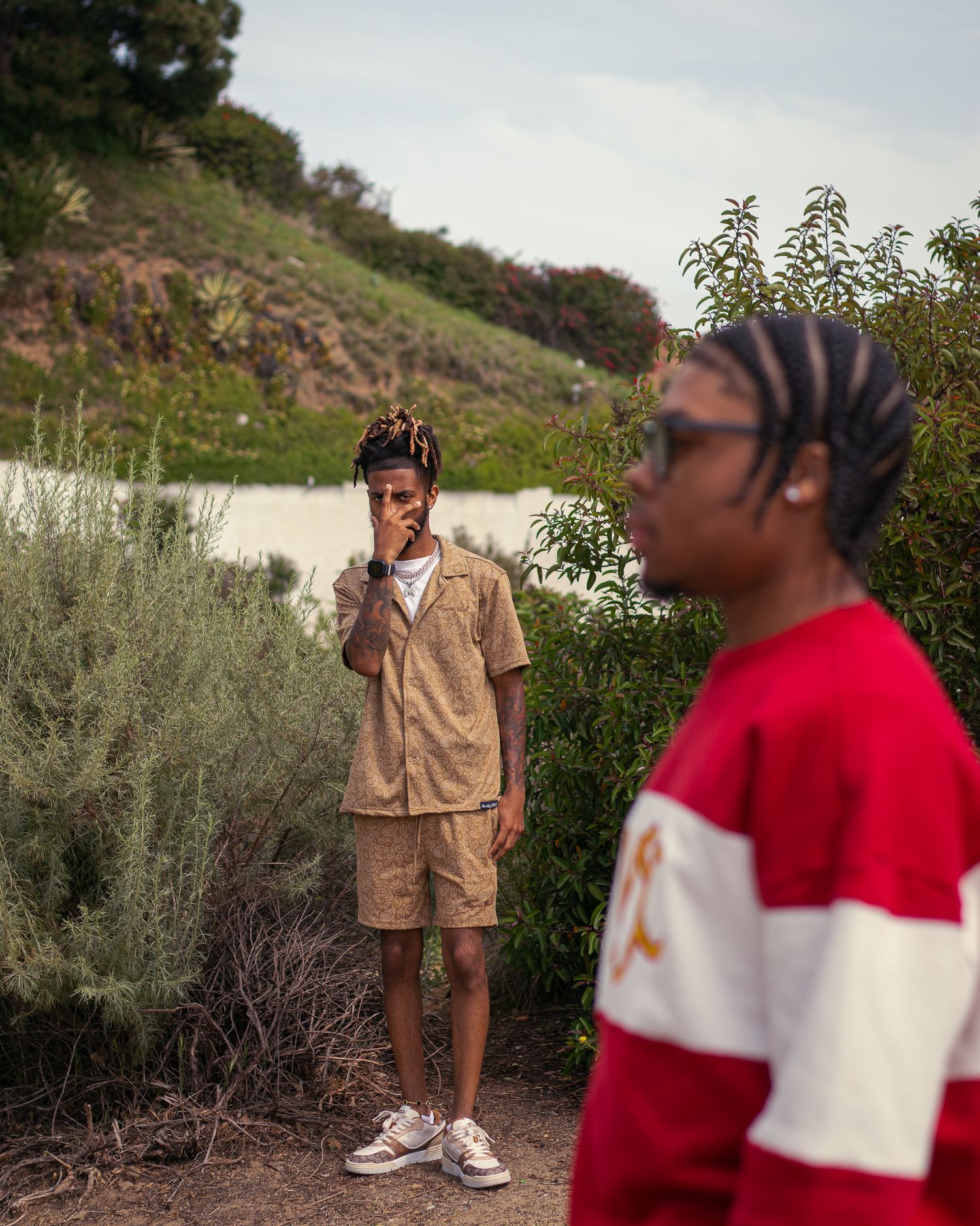 Candid outdoor photoshoot in casual attire among desert brush and hillside.