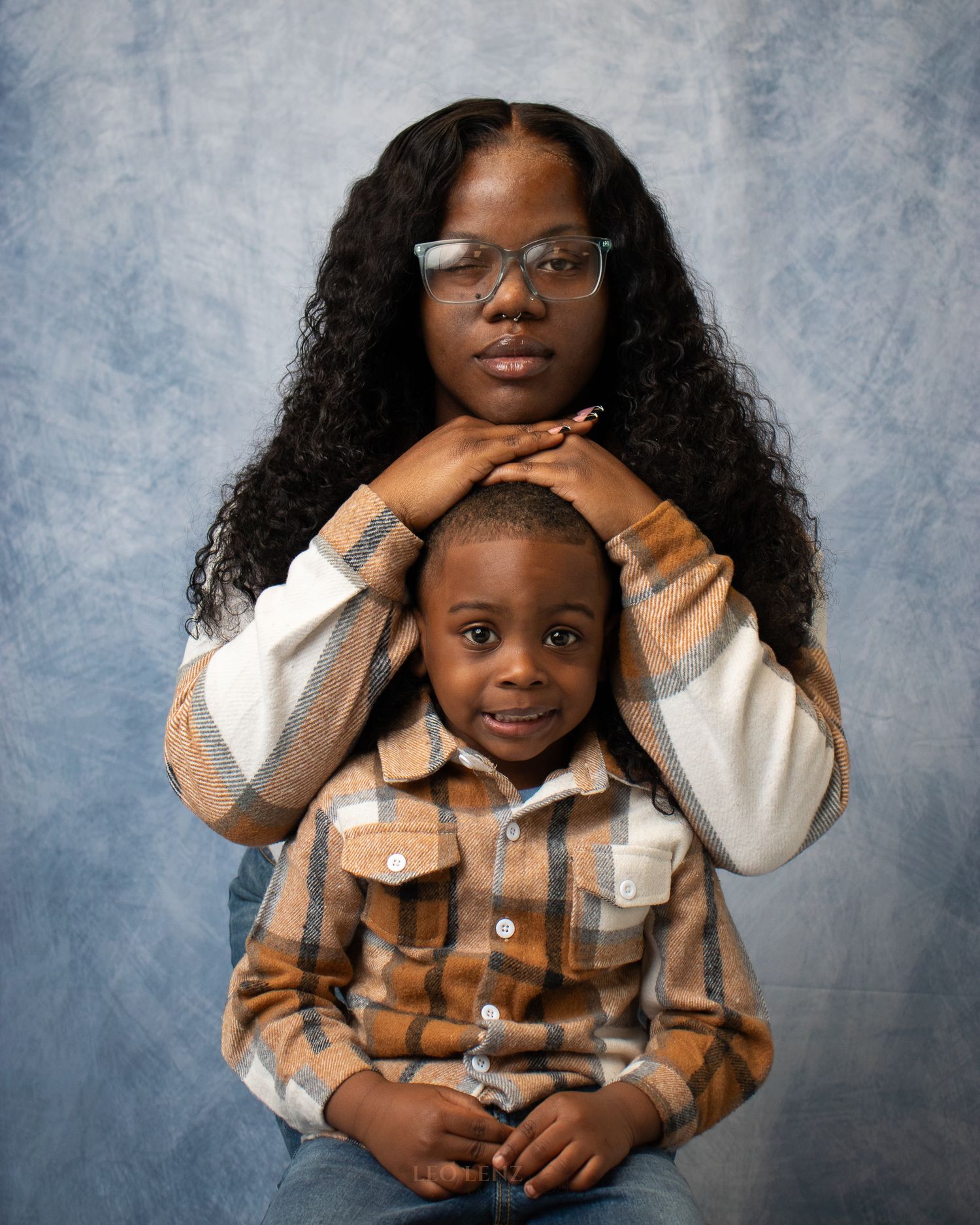 Studio portrait session against blue backdrop showing playful family interaction.