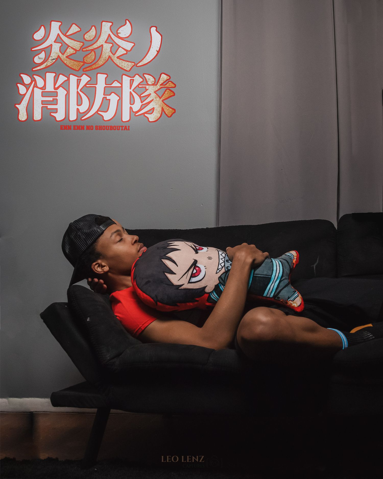 Person laying on dark leather couch with Asian characters displayed on wall behind.