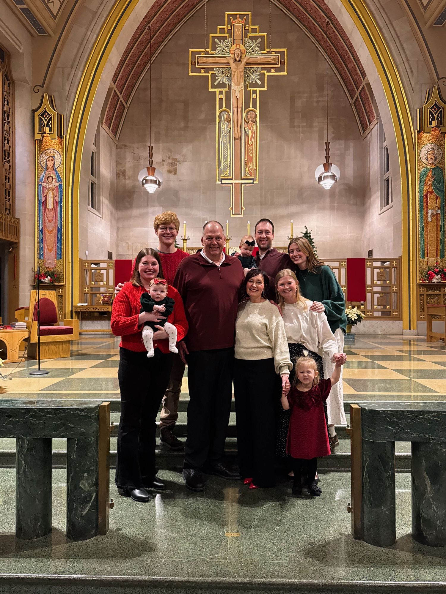 Family group photo inside a beautiful Catholic church with ornate gold cross and arched ceiling.