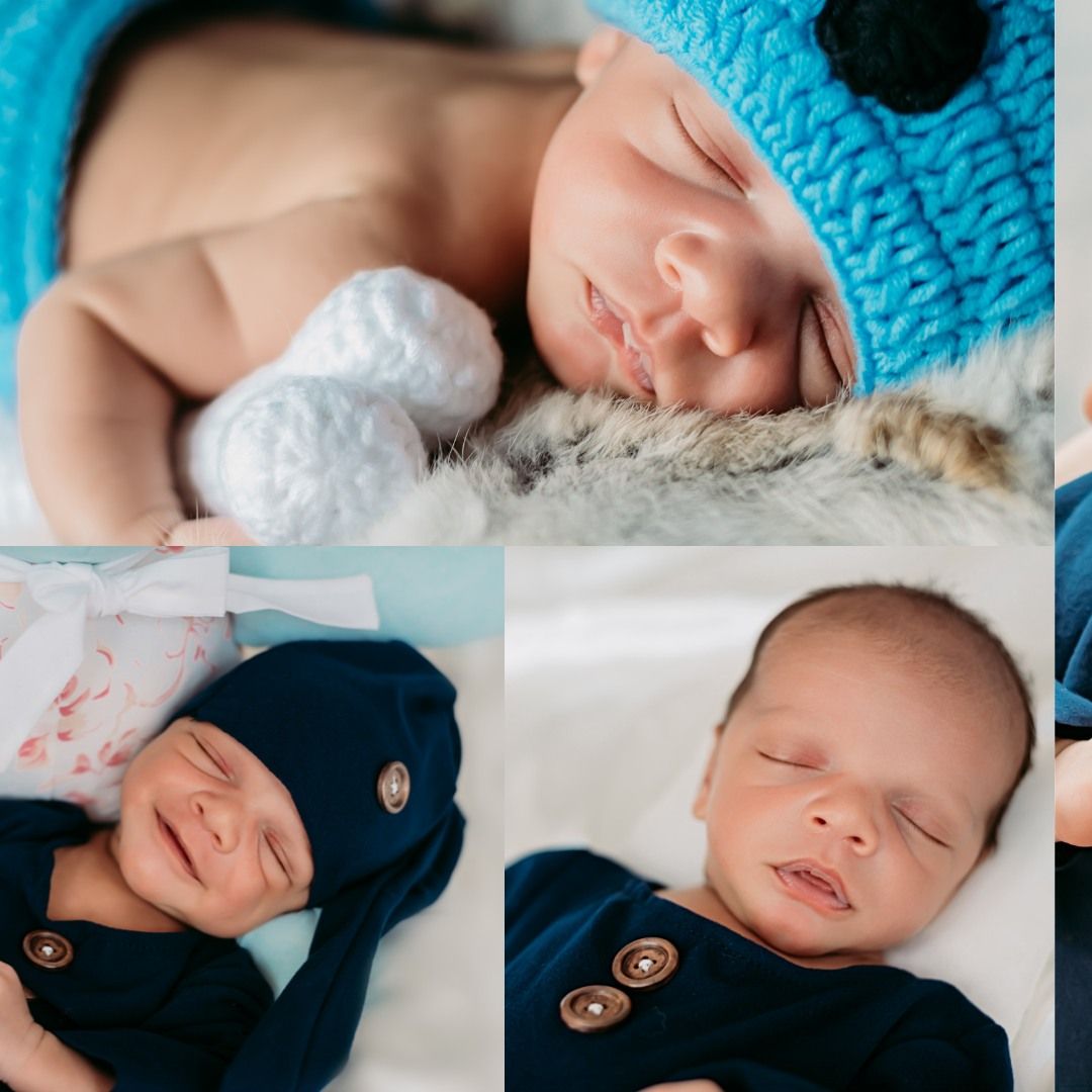 Sleeping newborn baby wearing dark blue clothing on white bedding.