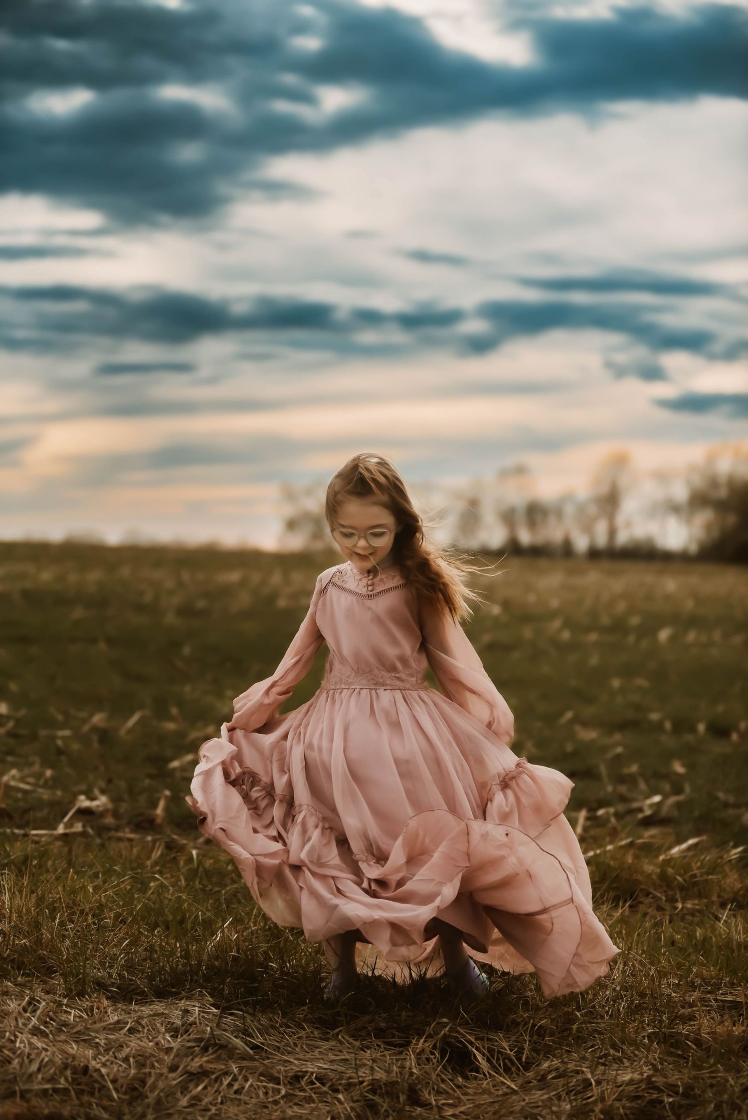Young dancer in pink dress spins gracefully in autumn field at dusk.