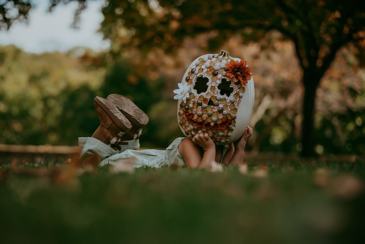 Person wearing a hockey mask lies in grass with dramatic lighting.