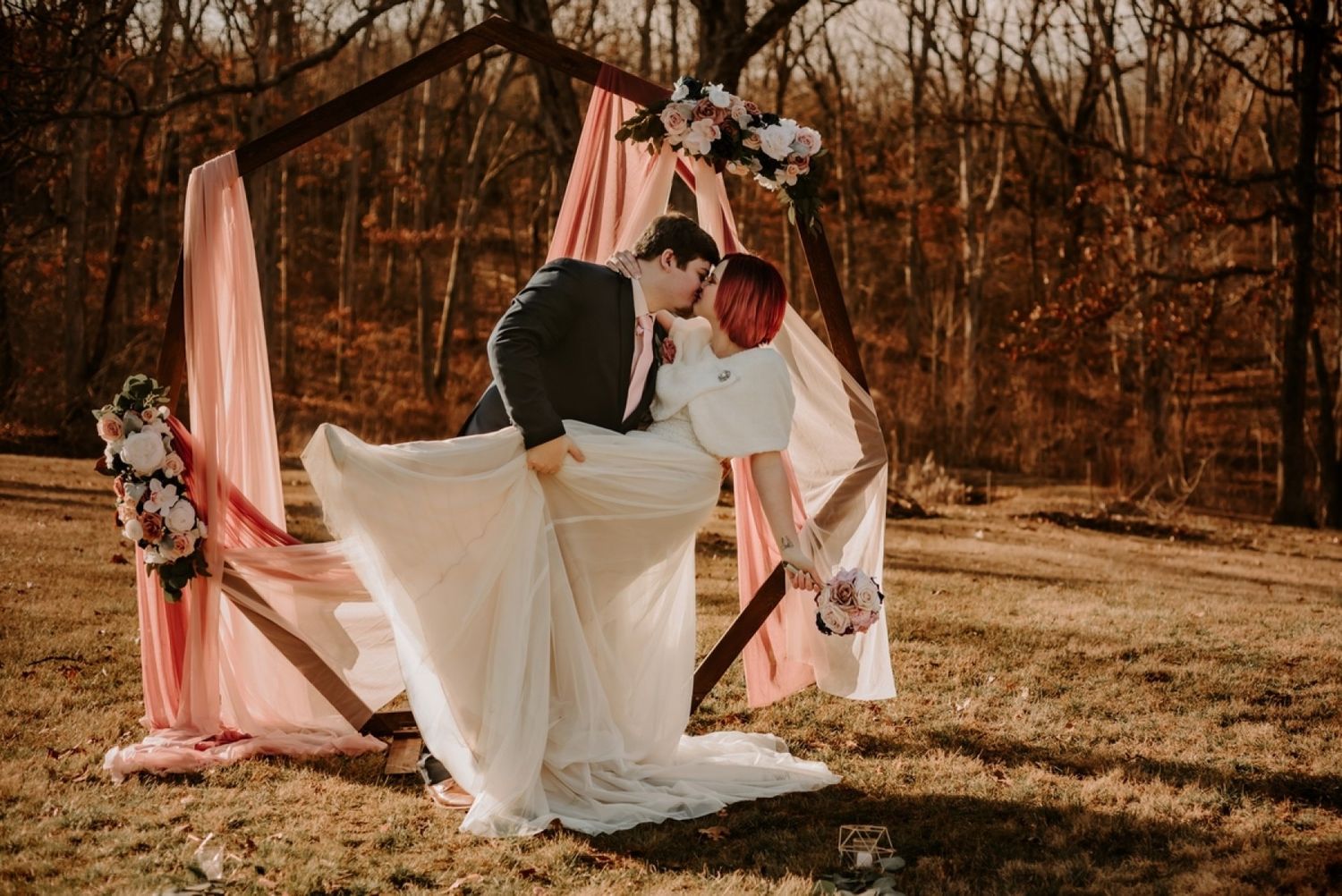 Wedding party helps adjust bride's dress train in an autumn outdoor setting.