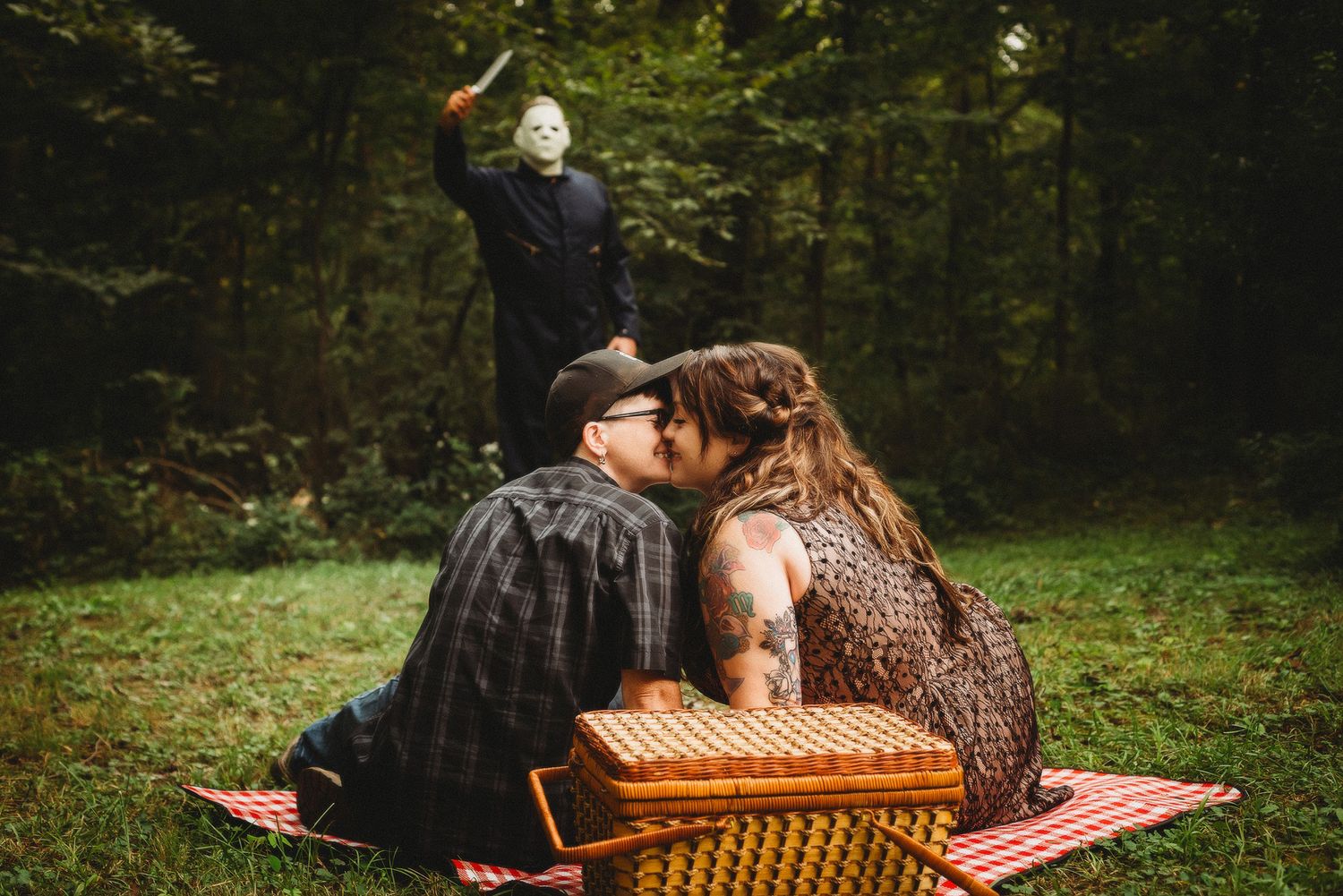 Couple having a romantic picnic on a blanket in a wooded area.