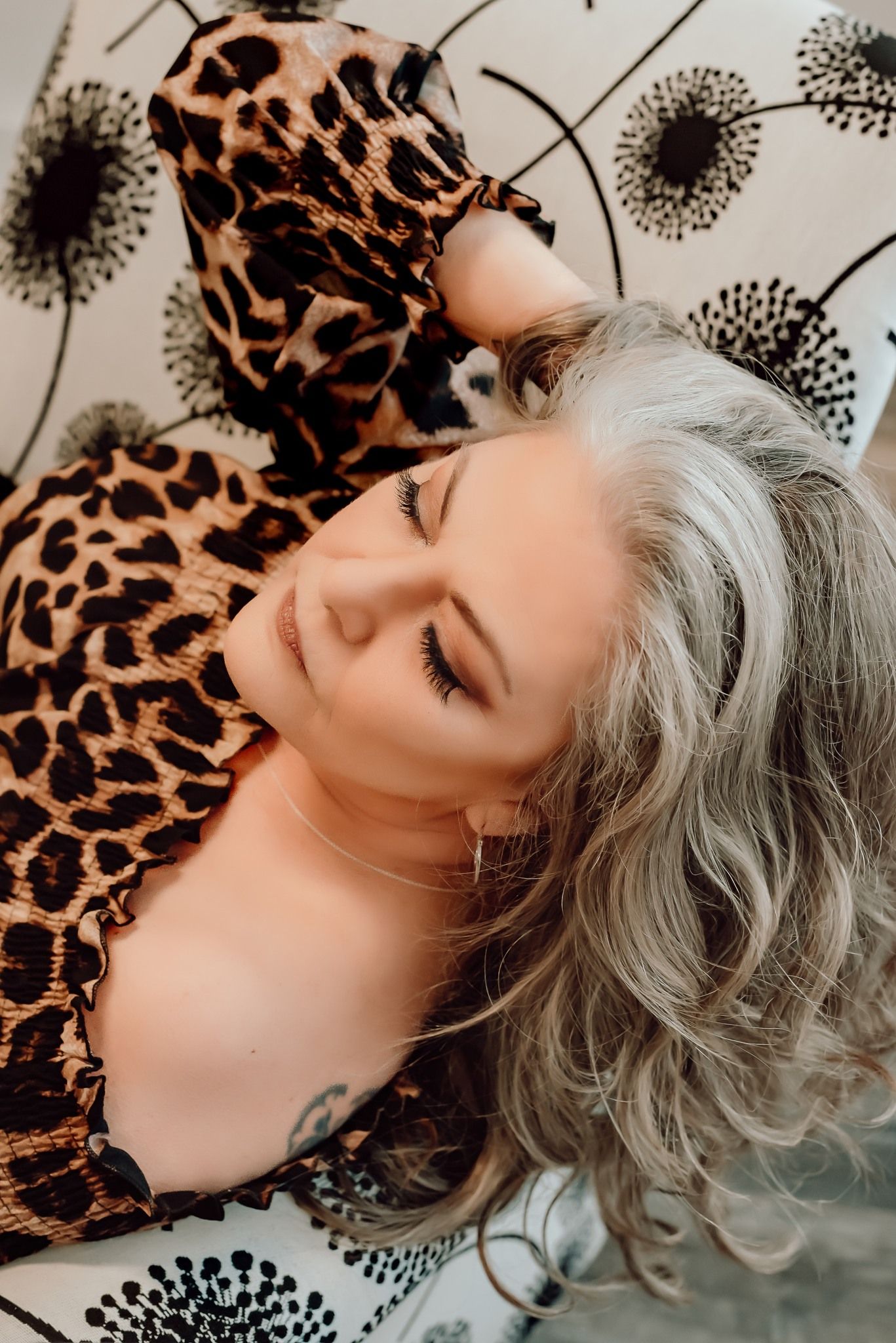 Artistic portrait with silver hair against leopard print background in dramatic lighting.
