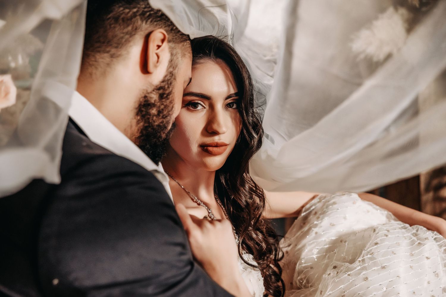 Romantic wedding portrait with flowing veil in dramatic lighting.