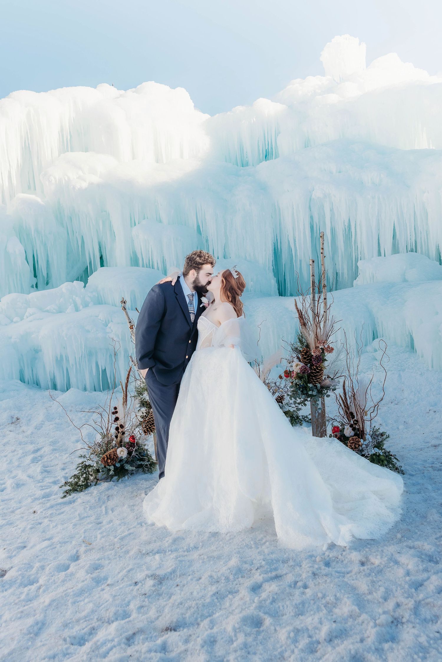 Romantic winter wedding portrait with couple standing before towering ice formations.