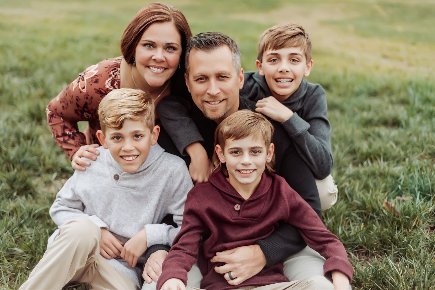 A family lounging together on grass during an outdoor photo session.