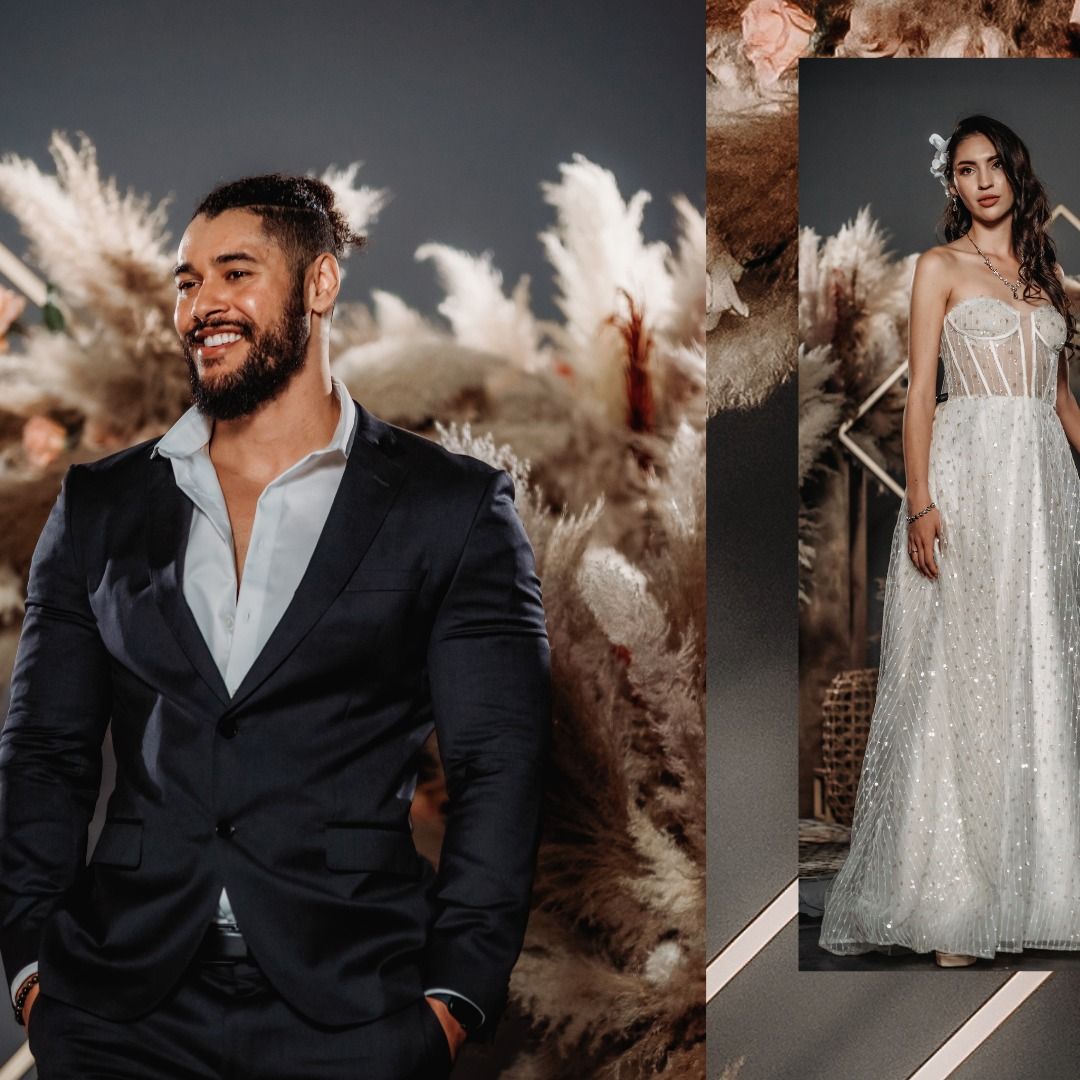 Wedding couple poses against moody backdrop with dramatic lighting and pampas grass decor.