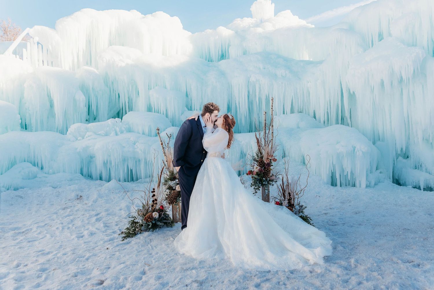 Winter wedding photos against stunning ice castle backdrop with frozen icicles.