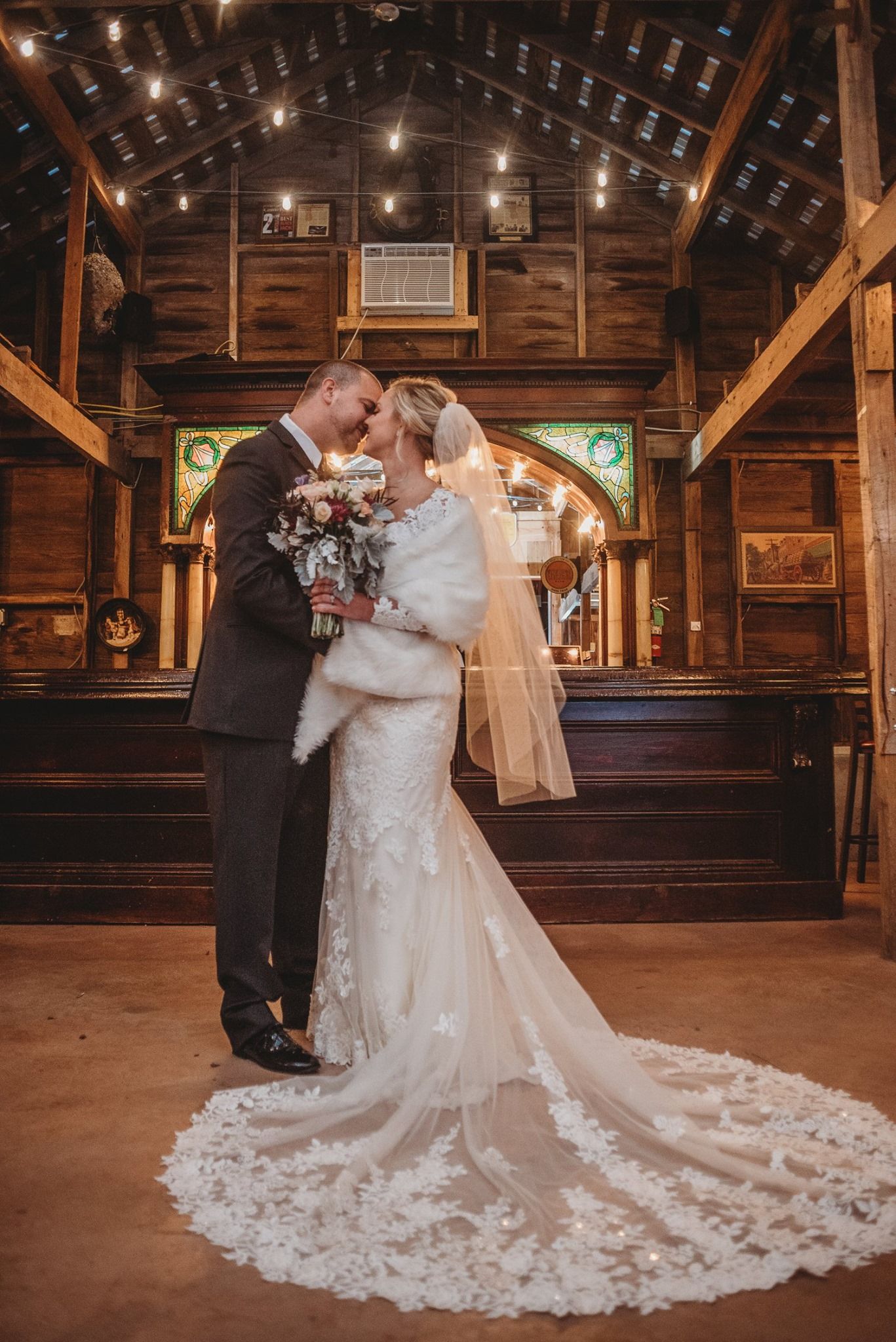 A romantic dance scene in a rustic barn with string lights and a flowing white wedding dress.