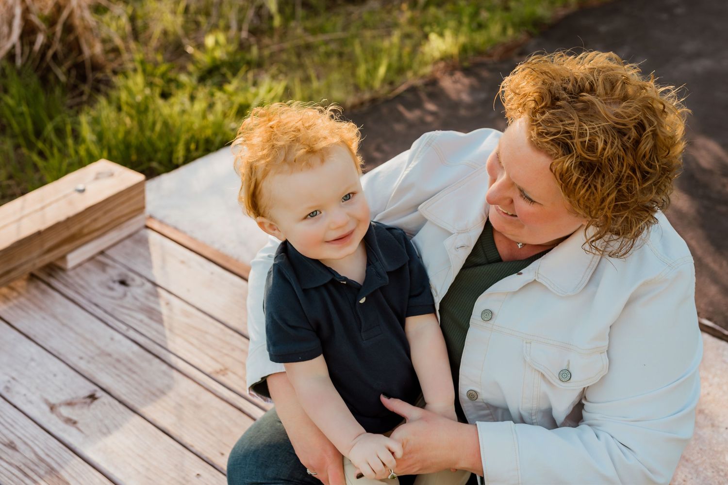 Mother and child sharing tender moment on wooden deck outdoors.