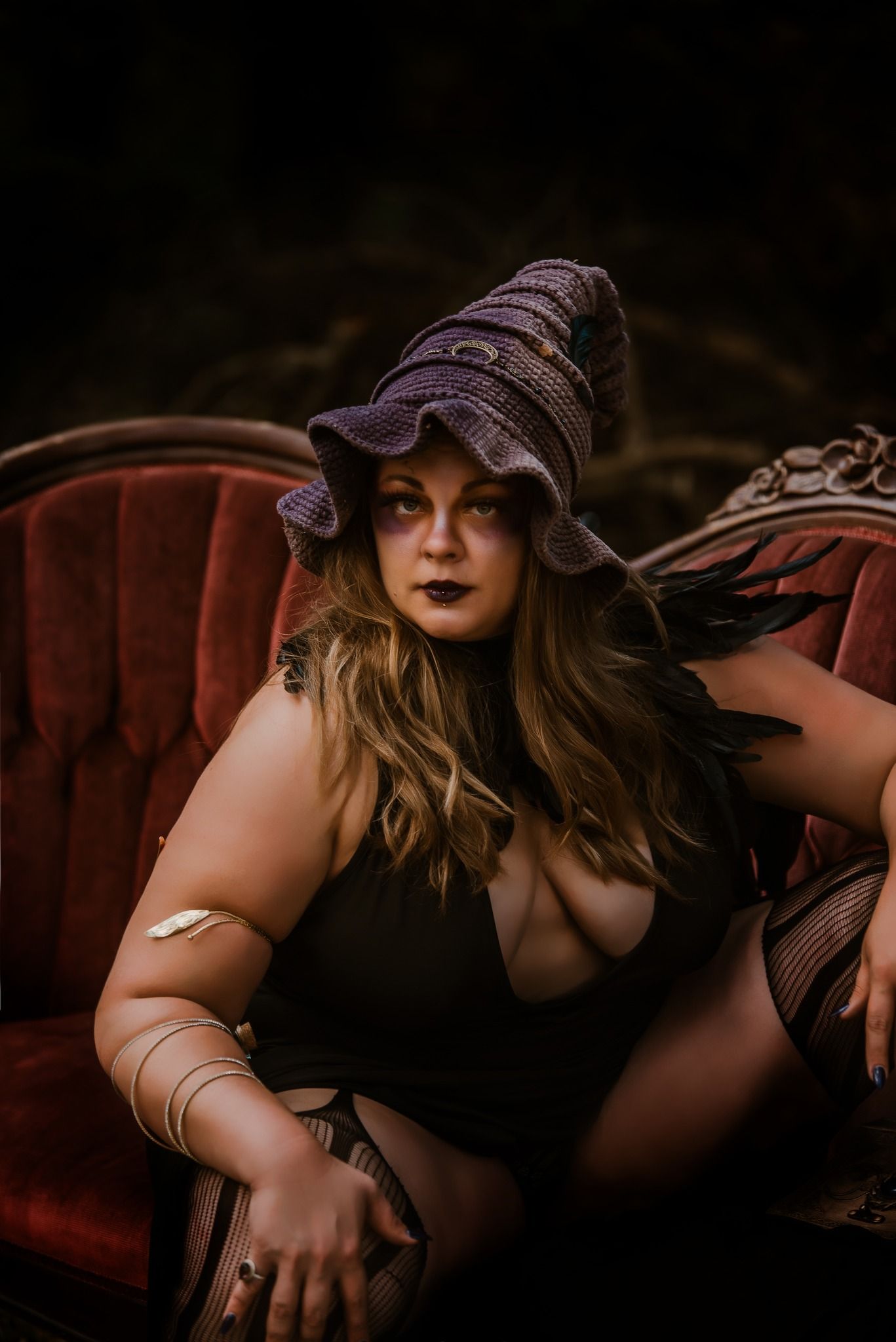 Artistic boudoir photoshoot featuring moody lighting and a vintage red velvet couch.