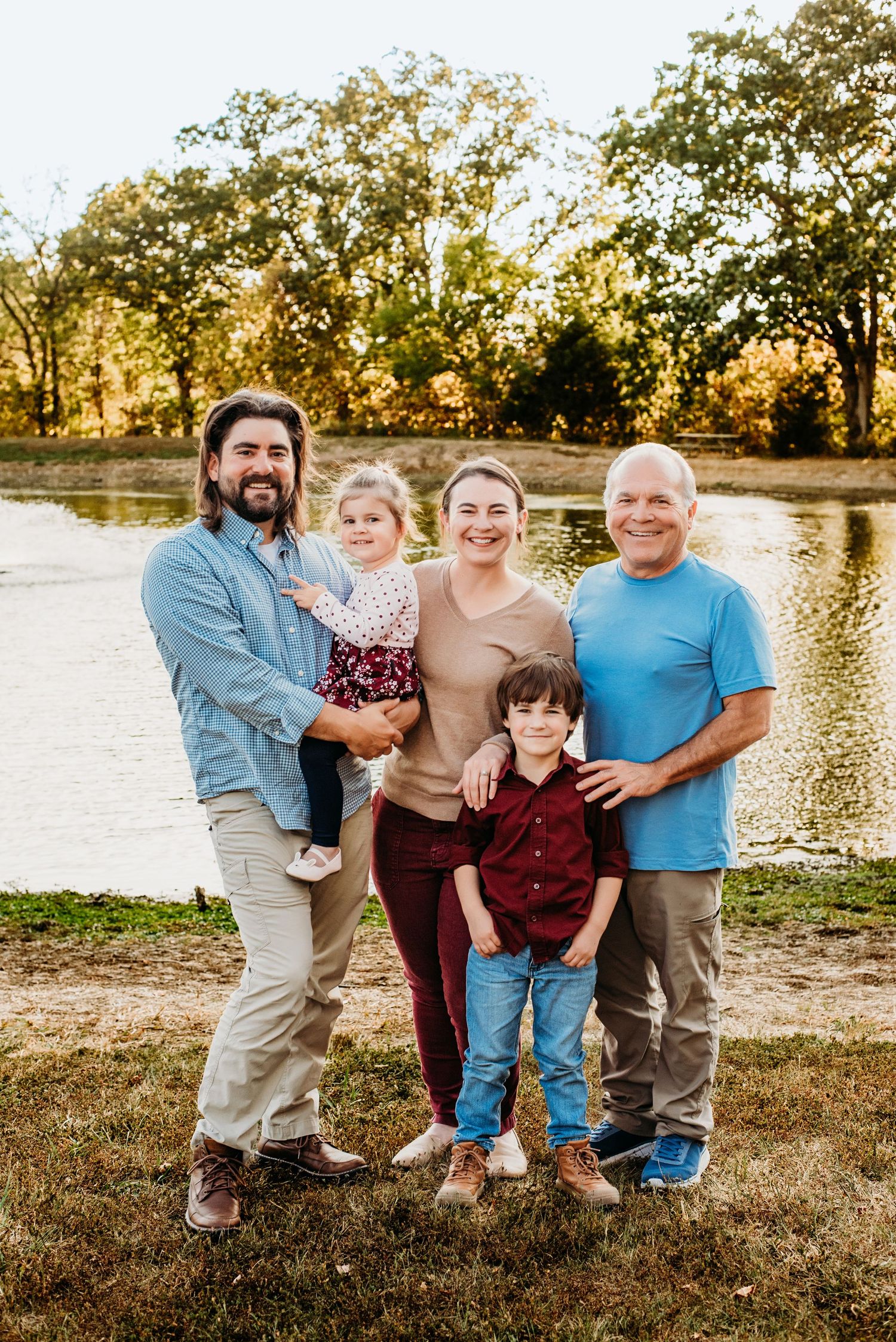 A group stands together by a lake at sunset during a casual outdoor photo session.