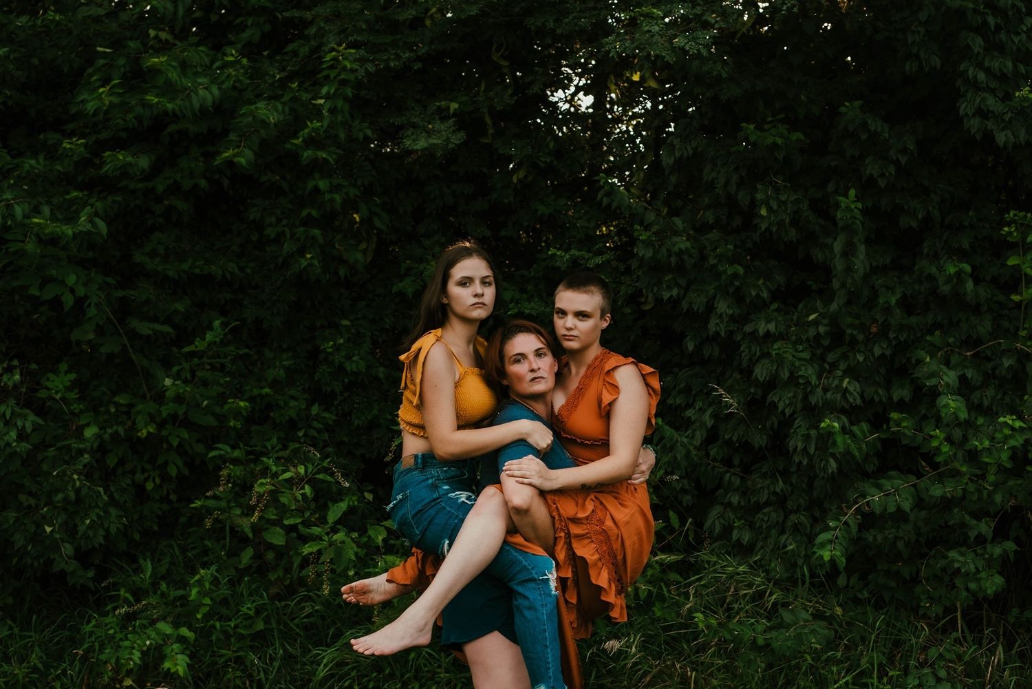 A candid family portrait in orange and blue outfits against green foliage.