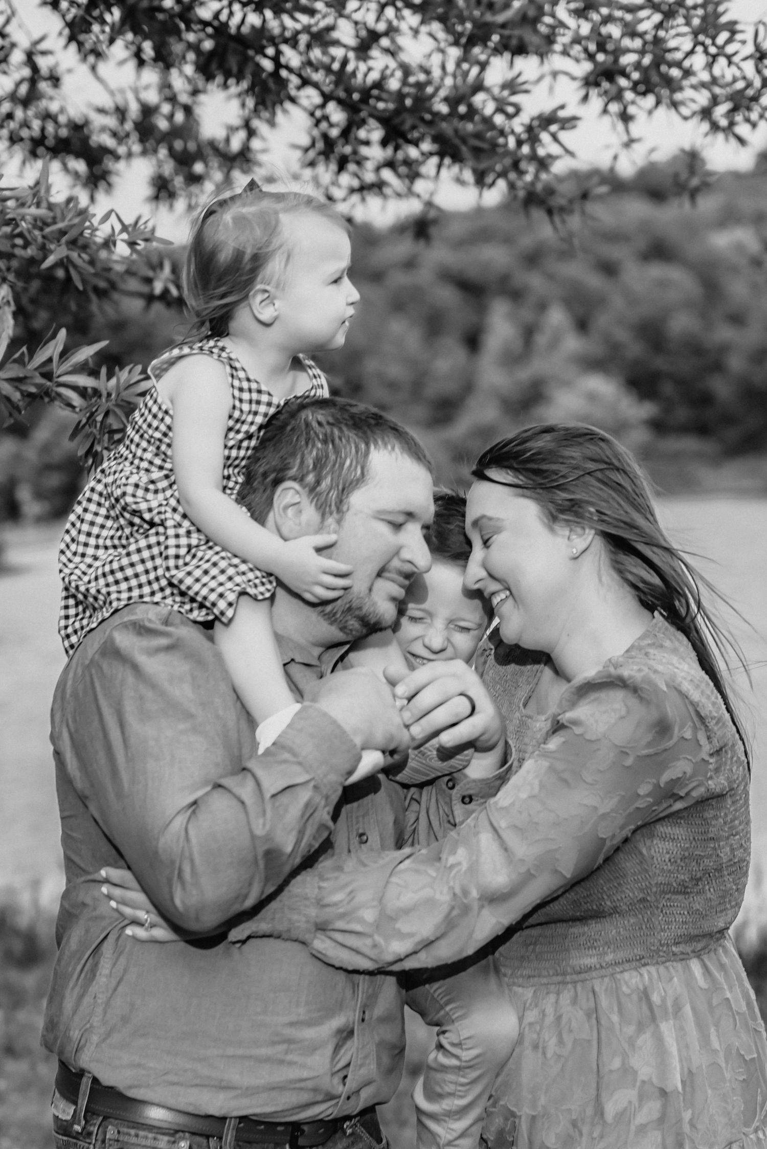 Intimate black and white family portrait showing playful interaction outdoors.