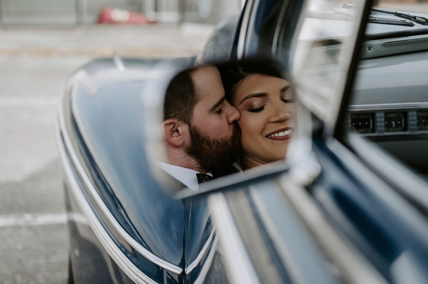 Romantic couple sharing intimate moments inside a car on their wedding day.