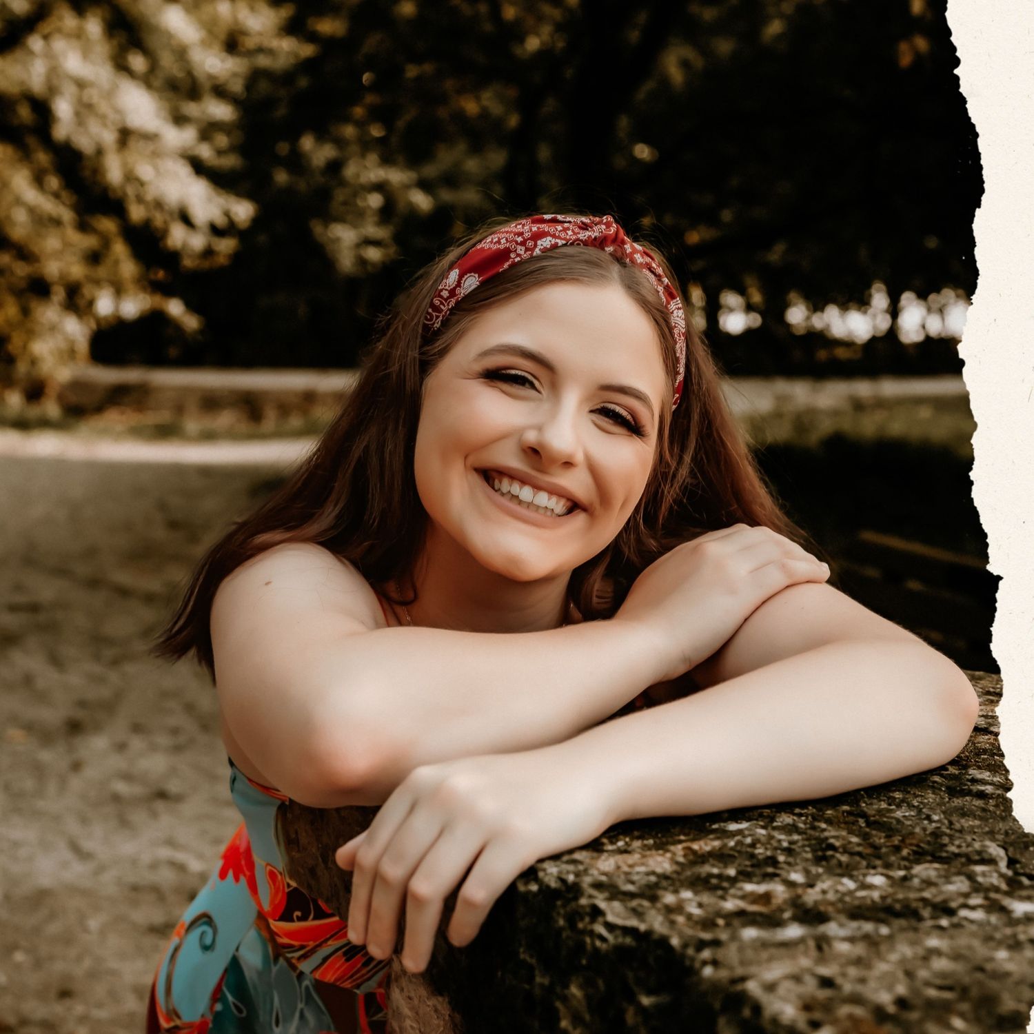 A floral dress and red headband create a dreamy summer portrait in warm lighting.