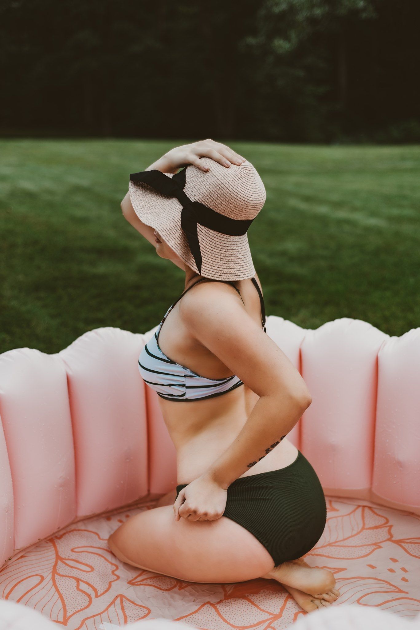 Person relaxing on a pink inflatable pool float in a backyard setting.