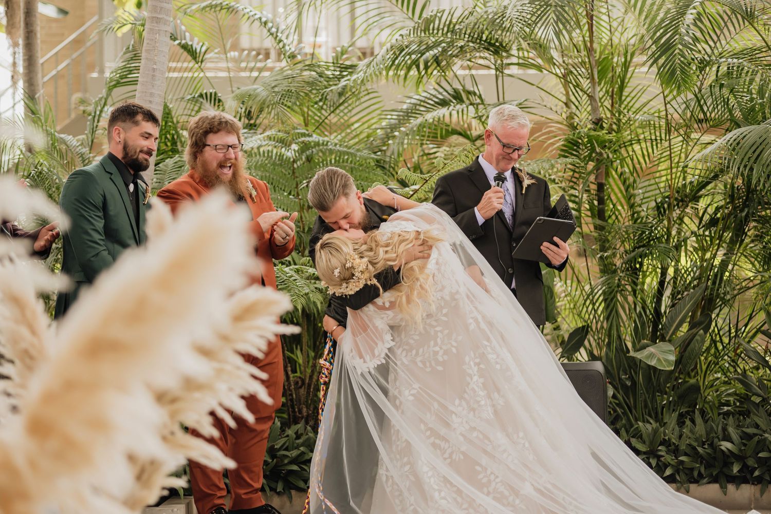 An emotional wedding ceremony moment in a lush greenhouse setting with tropical plants.