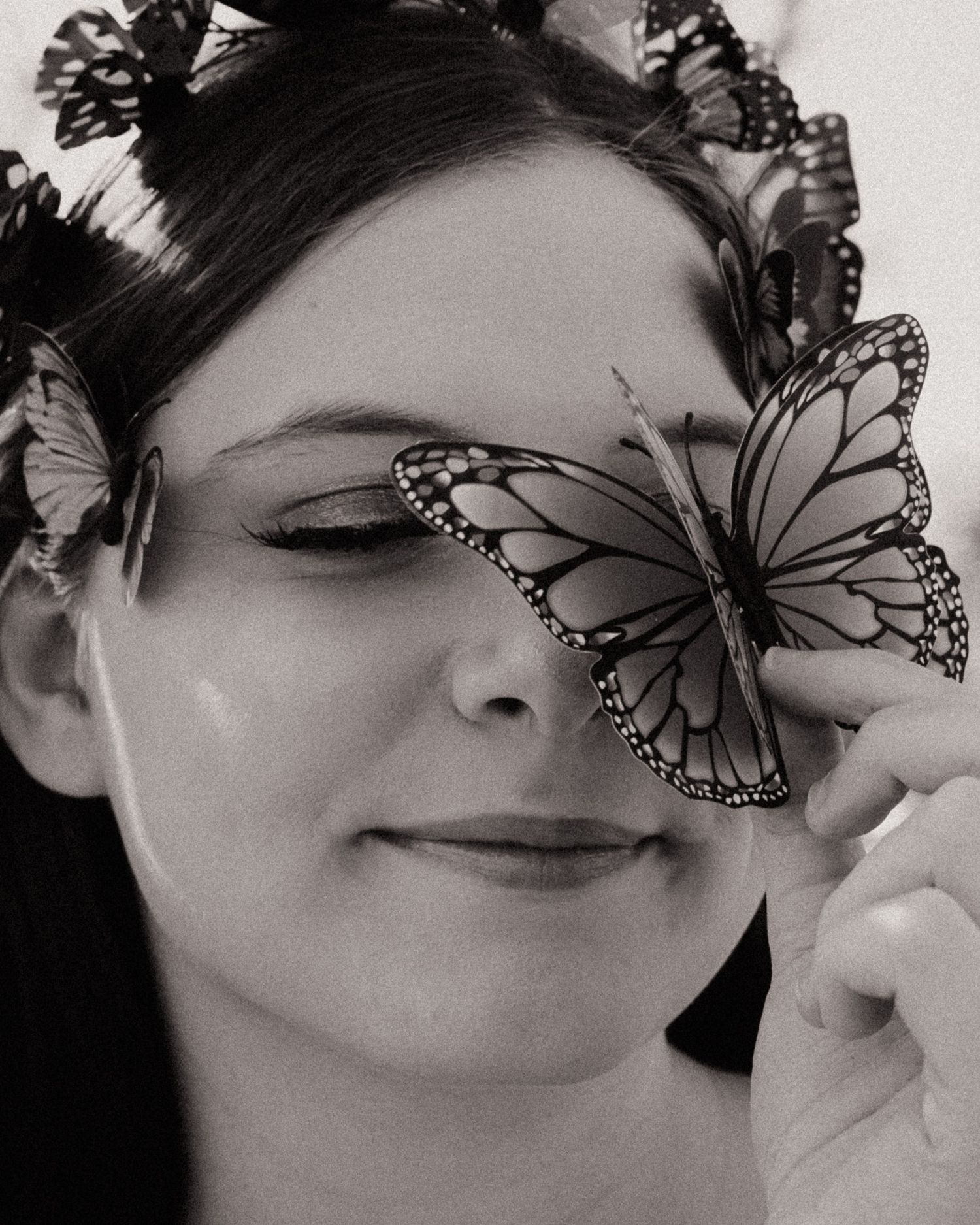 Artistic black and white portraits with delicate butterfly overlays creating ethereal effect.