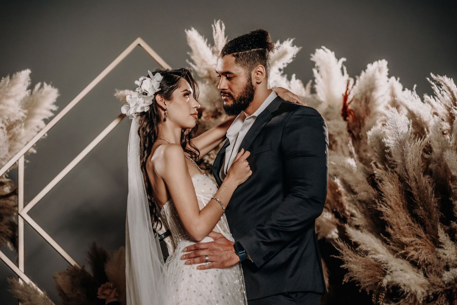 Romantic wedding portraits with dramatic pampas grass and geometric backdrop.