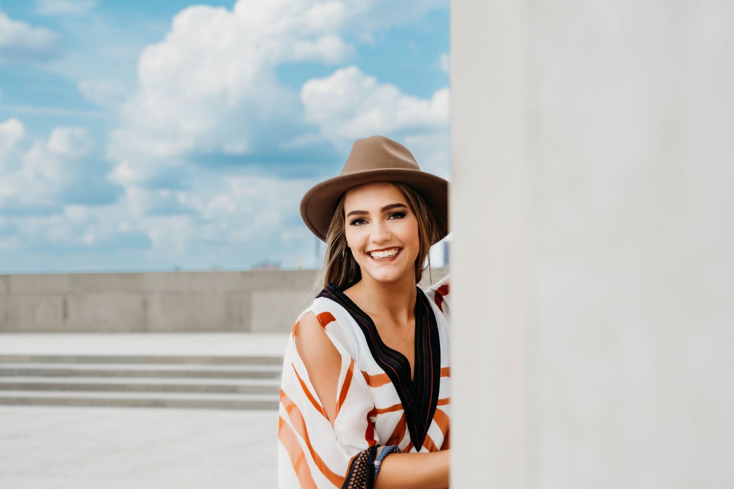 Lifestyle portrait session against white wall with bright blue sky.
