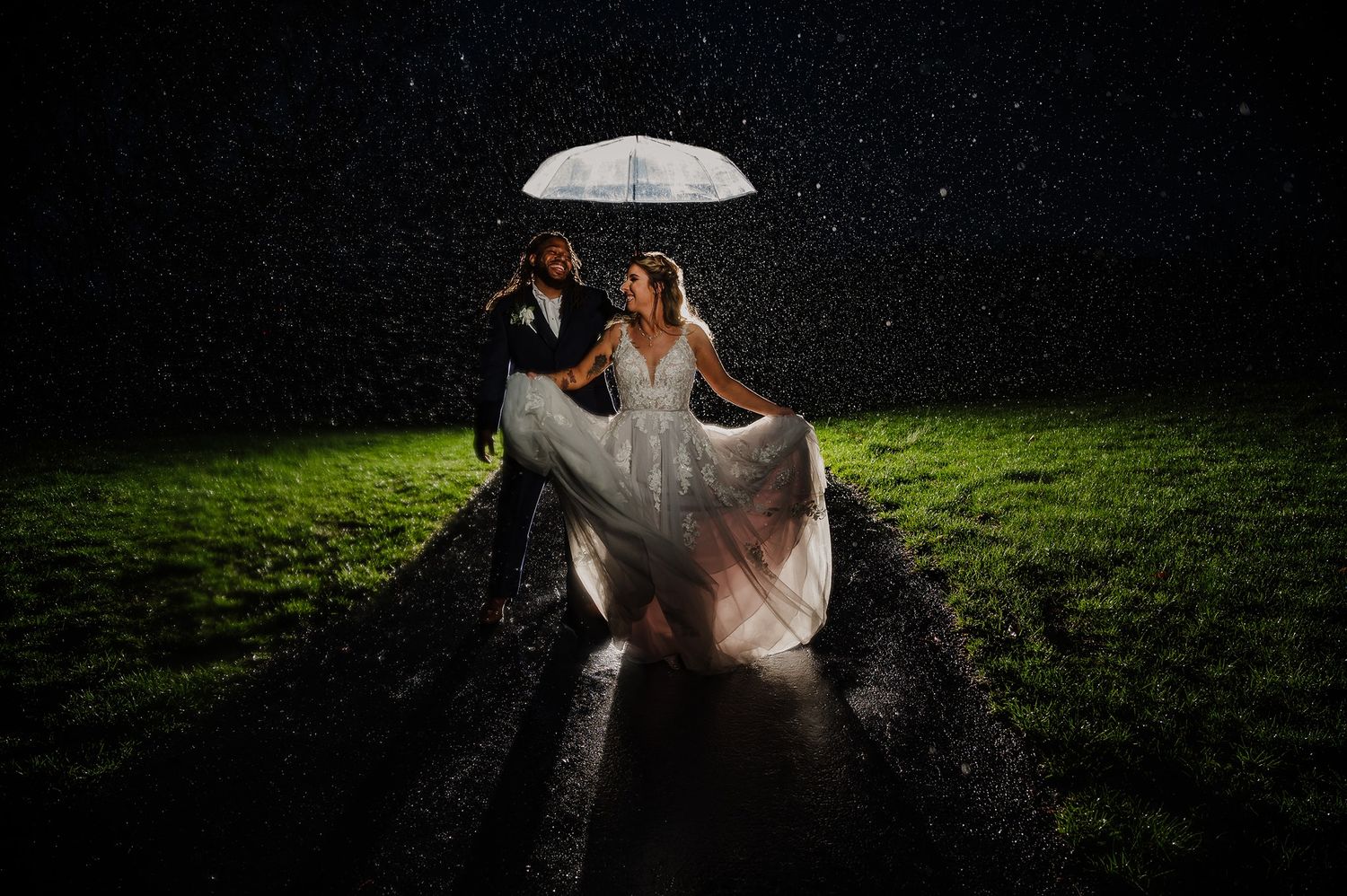 A nighttime wedding photo with an illuminated umbrella creating dramatic lighting.