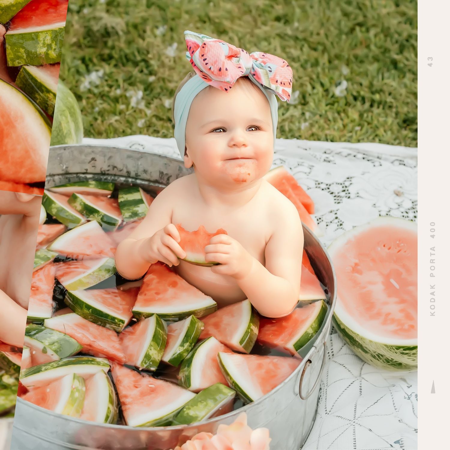 Baby wearing mint headband surrounded by fresh watermelon slices on white blanket.