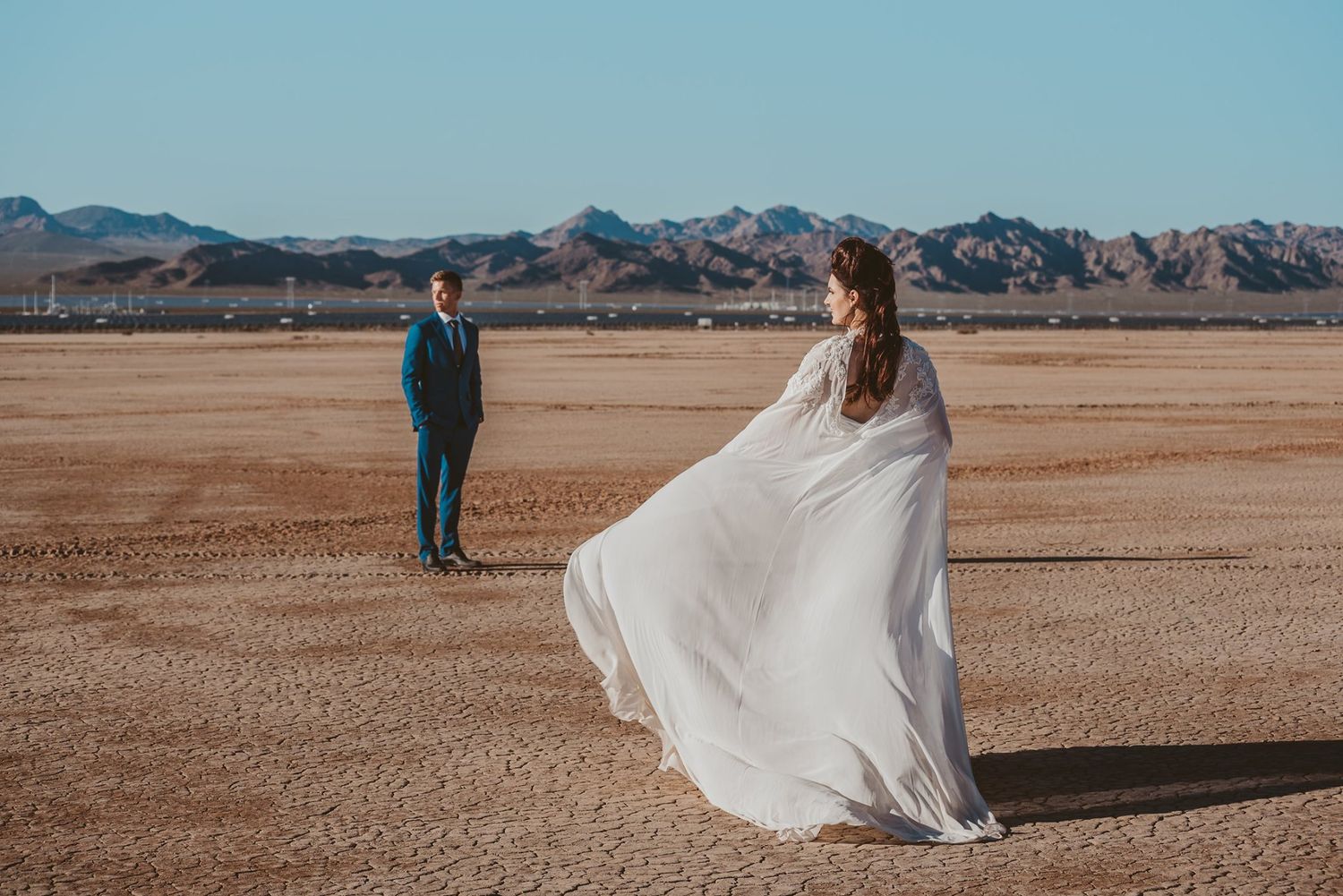 A flowing white dress catches the wind against a desert mountain backdrop.